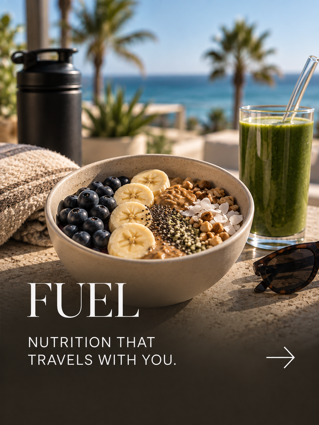A bowl of oatmeal topped with banana slices, blueberries, nuts, and seeds on a table outdoors with a beach in the background. There is a green smoothie, sunglasses, a water bottle, and a towel nearby.