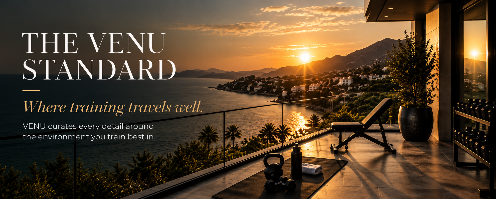 Hotel fitness room with workout equipment overlooking a coastal sunset view.