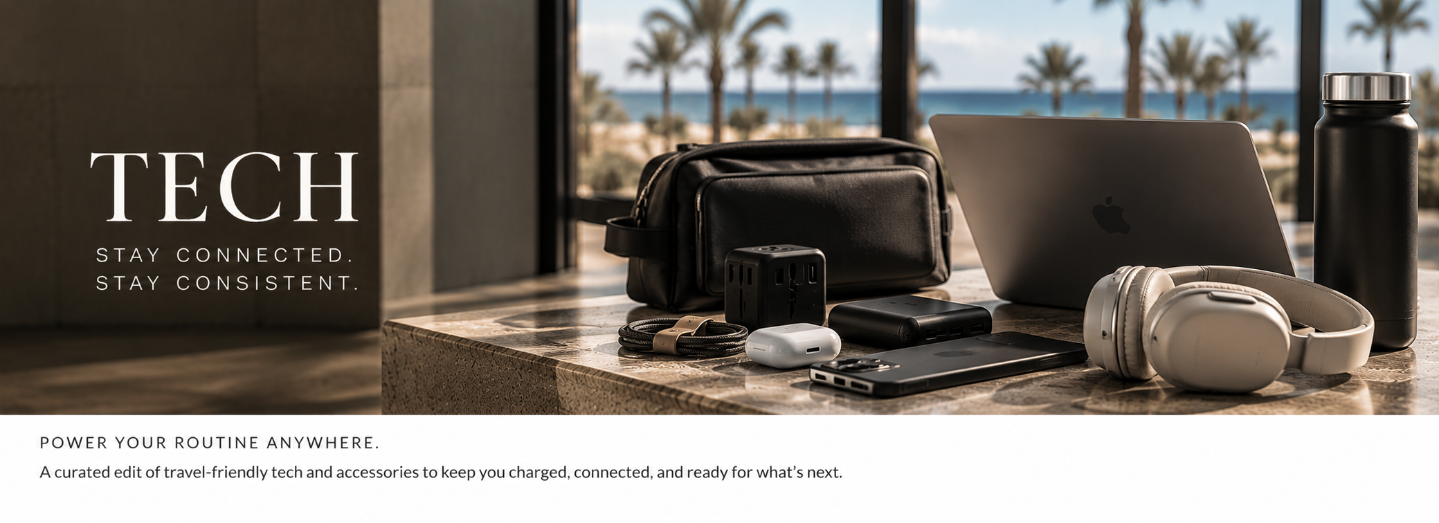 Travel tech accessories on a marble table with a laptop, headphones, a water bottle, a black bag, chargers, and a phone, with a view of palm trees and the ocean outside a window.