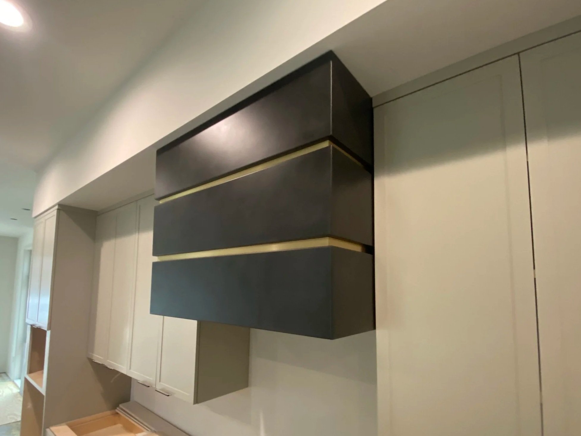 Custom Blackened Steel Range Hood with Brass Inlay - A striking, tiered range hood crafted from blackened steel and accented with brushed brass banding, custom-built to anchor a modern kitchen renovation. This handmade metal hood combines industrial 