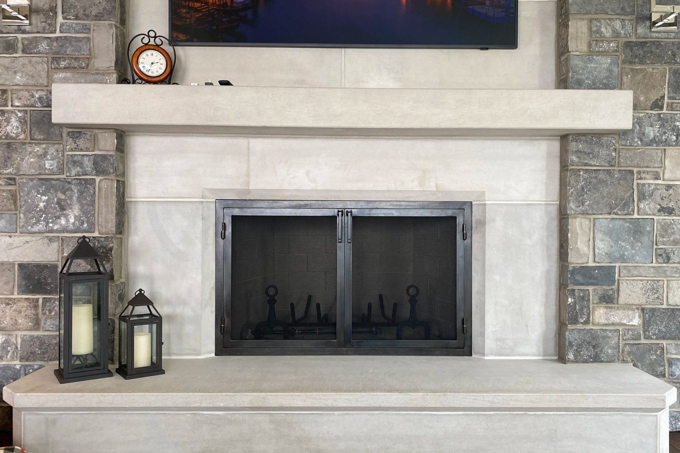 Custom fireplace screen doors by Red Iron Studio, hand-forged in blackened iron with a clean, minimalist frame and fine mesh panels to complement a modern stone-and-concrete hearth. This custom fireplace screen delivers understated, contemporary craf