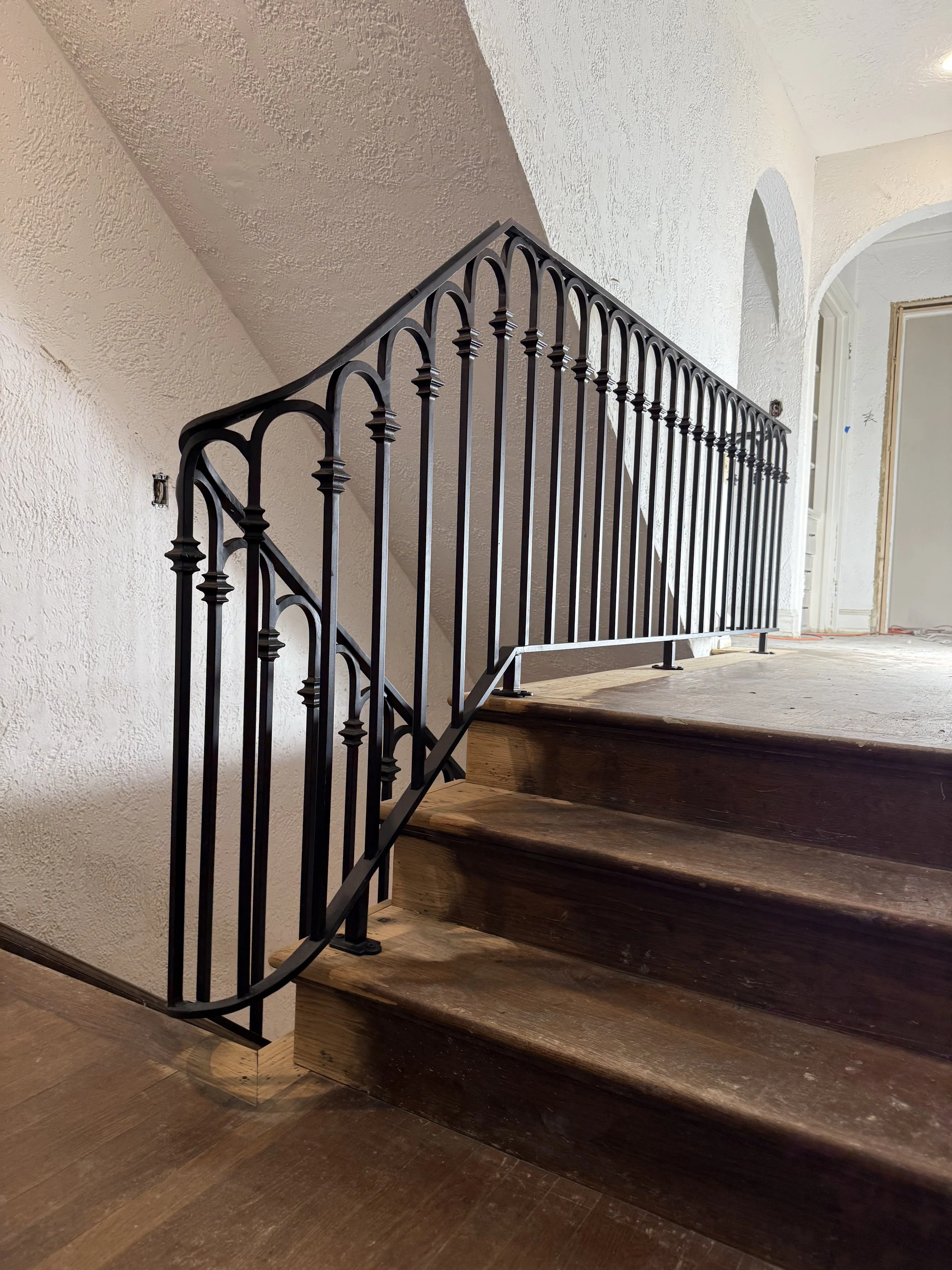 Artistic hand-forged wrought iron stair railing featuring sculptural branch and twig designs by Red Iron Studio, paired with a curved wood handrail and rich walnut stair treads in an elegant staircase.
