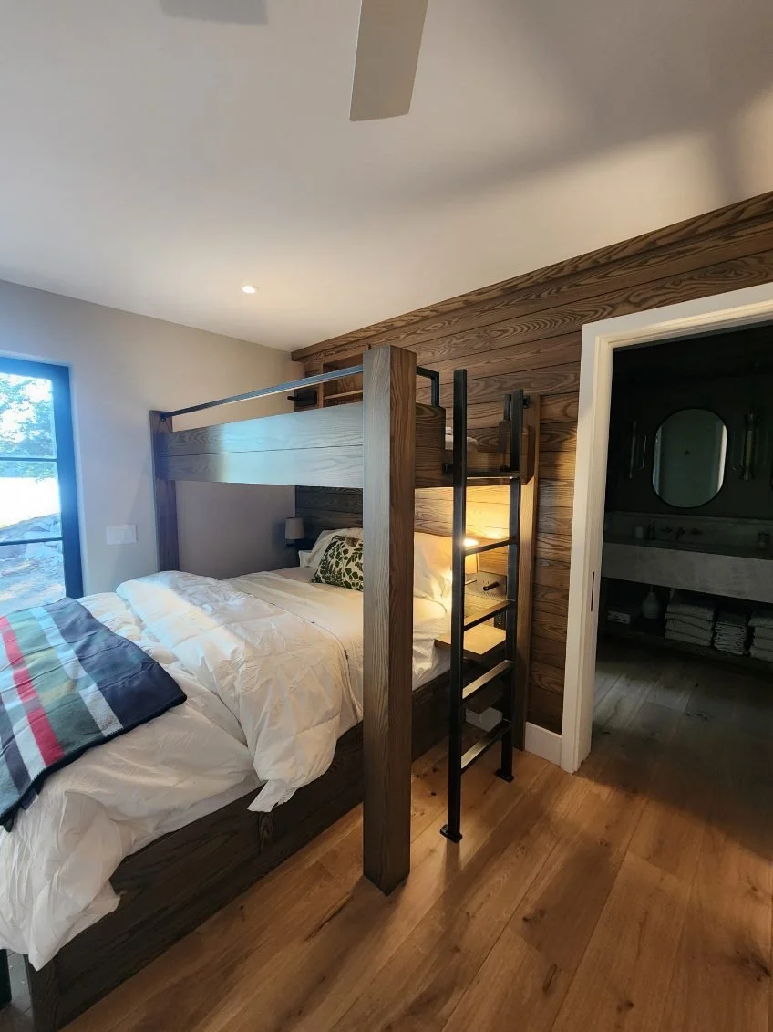 This custom-fabricated steel ladder and safety railing complements a built-in wood bunk bed, combining sleek industrial metalwork with warm, natural materials for a cozy lake house guest room. Durable and space-efficient, this custom bunk bed hardwar