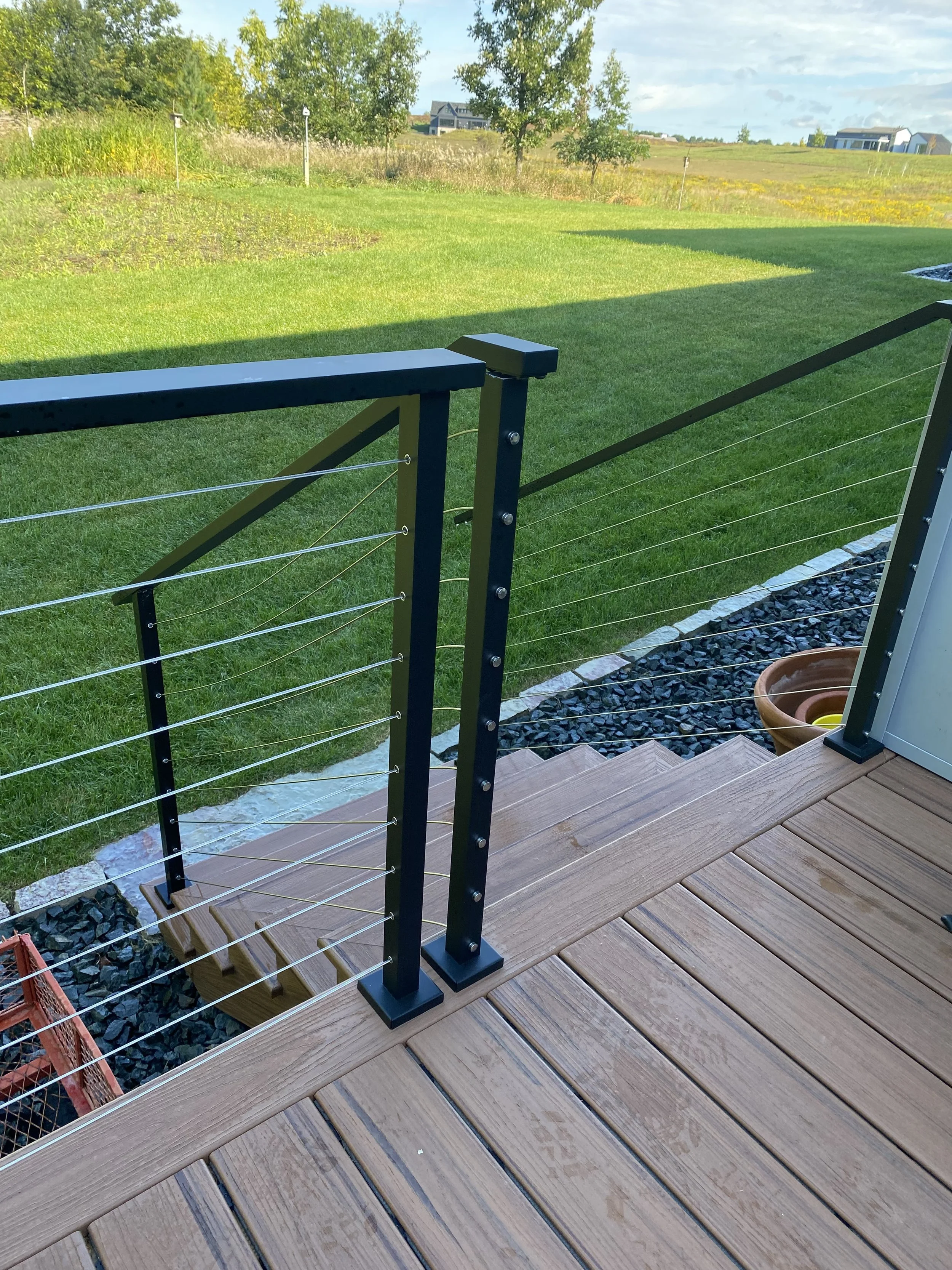 Modern black aluminum cable railing with stainless steel horizontal cables, custom-installed by Red Iron Studio for a backyard deck and staircase. This sleek outdoor cable rail system offers durable, low-maintenance safety while preserving unobstruct
