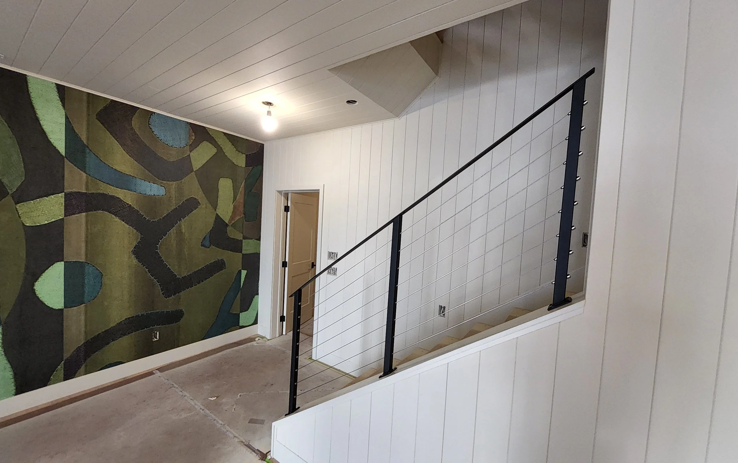 Modern black steel cable railing with horizontal stainless steel cables and slim square posts, custom-crafted by Red Iron Studio for a stylish stairway. This minimalist cable rail design offers an open, contemporary look with unobstructed sightlines,