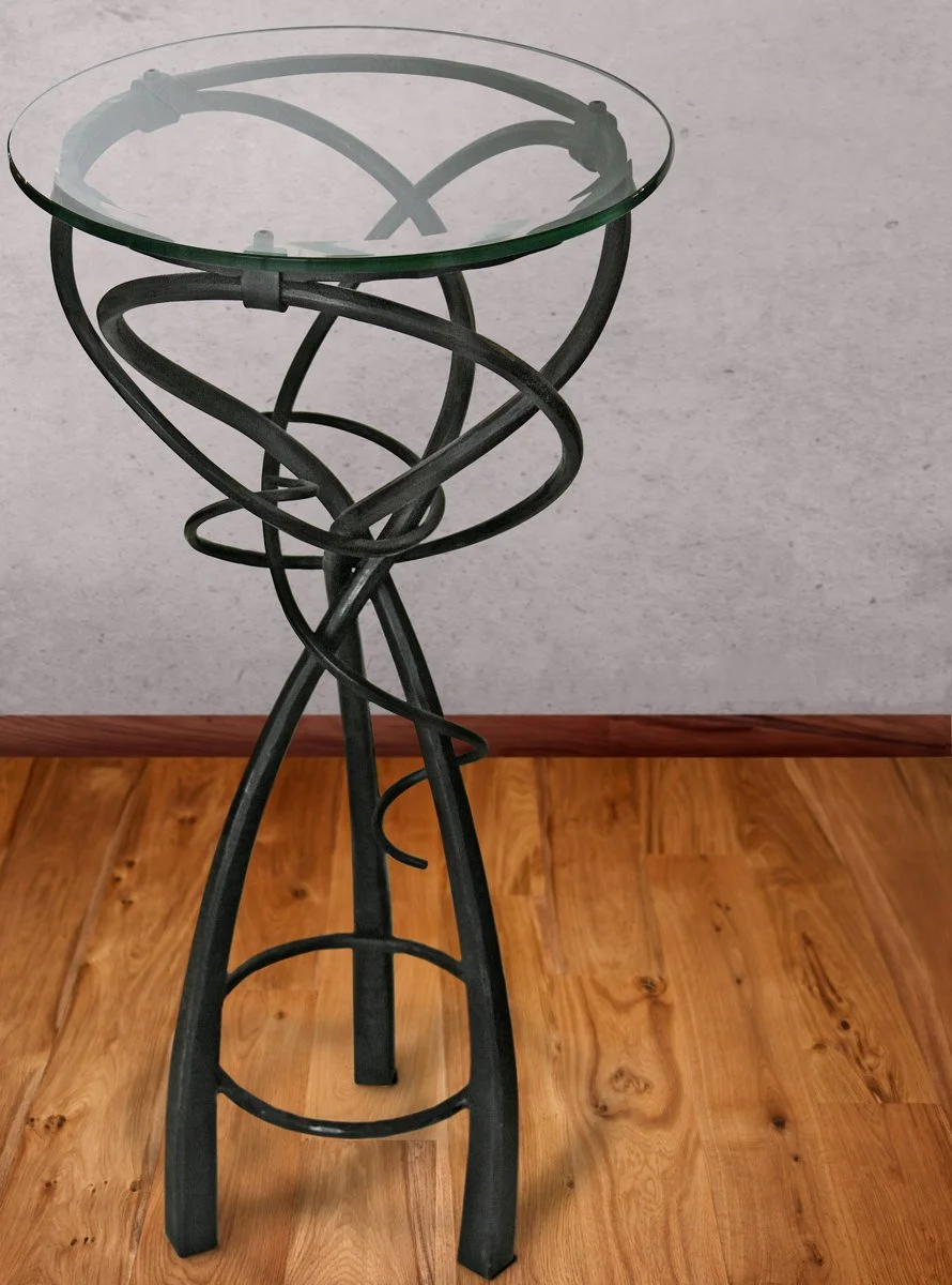 Handcrafted Iron Pedestal Table with Round Glass Top - This elegant hand-forged iron pedestal table features a swirling, hand-twisted metal base topped with a round glass tabletop, blending organic sculptural form with functional design. Ideal as an 