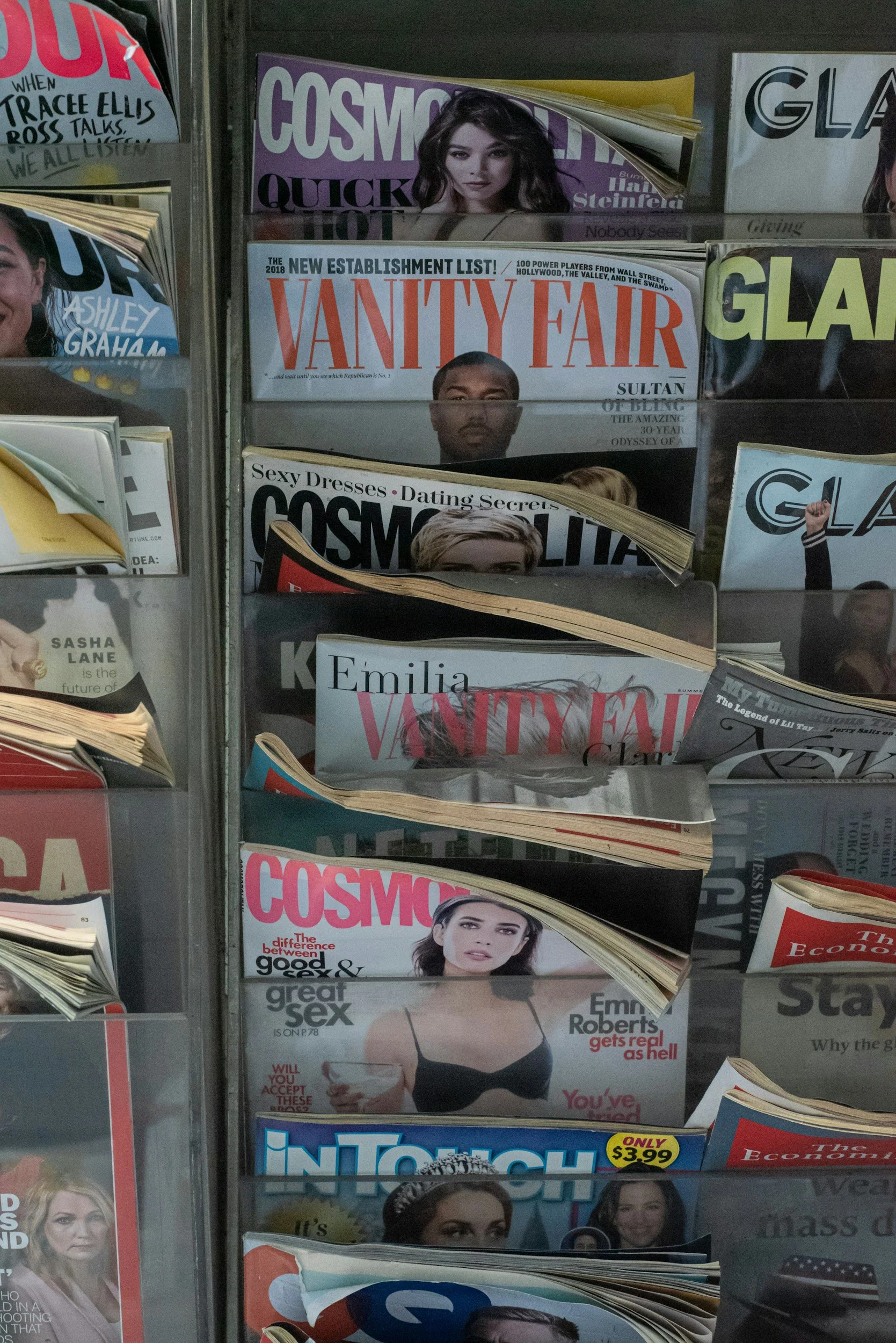 Magazine rack with various magazines including Vanity Fair, Cosmopolitan, Glamour, and InTouch, featuring celebrity covers.