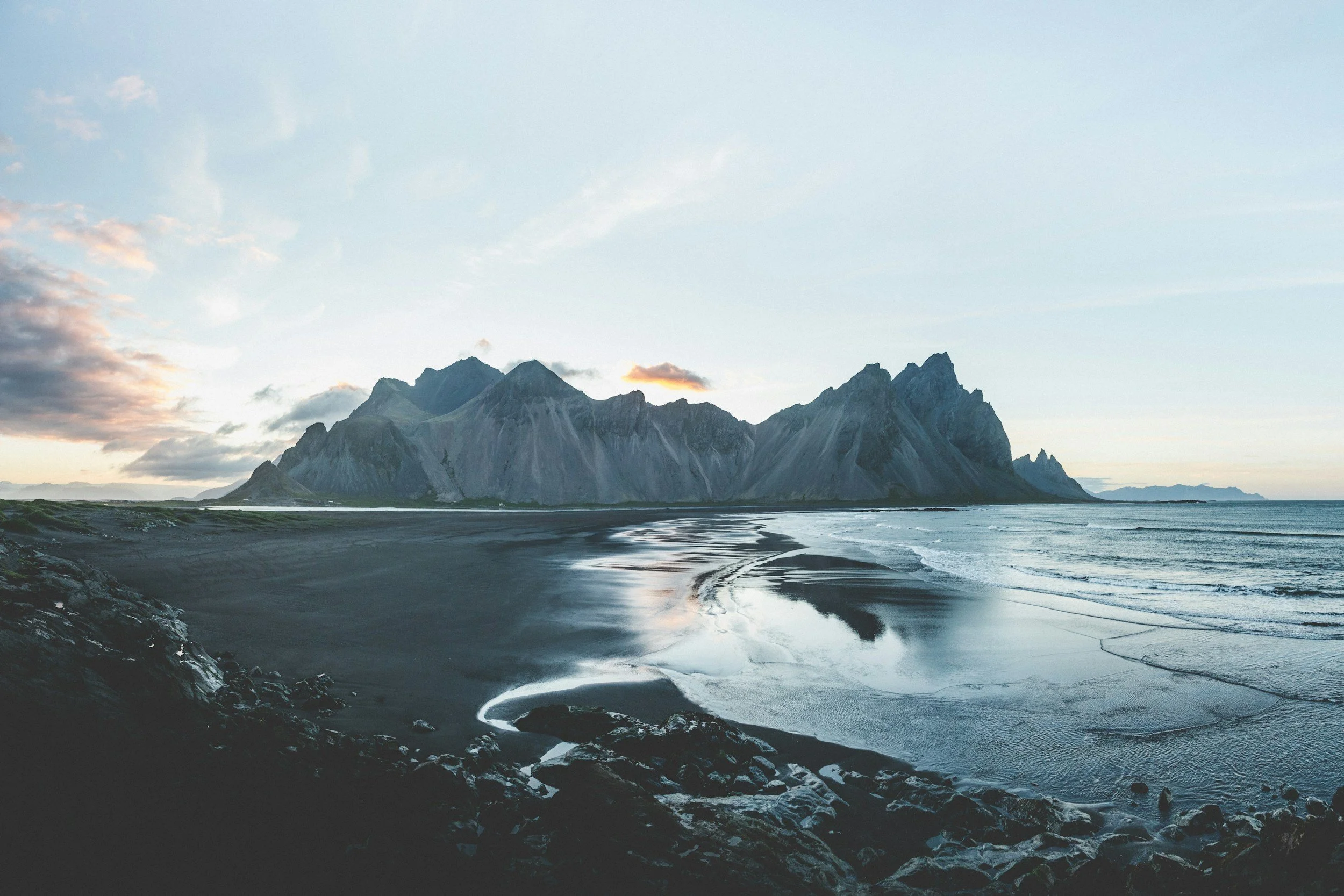 Scenic view of a mountain range reflected in the water with a cloudy sky.