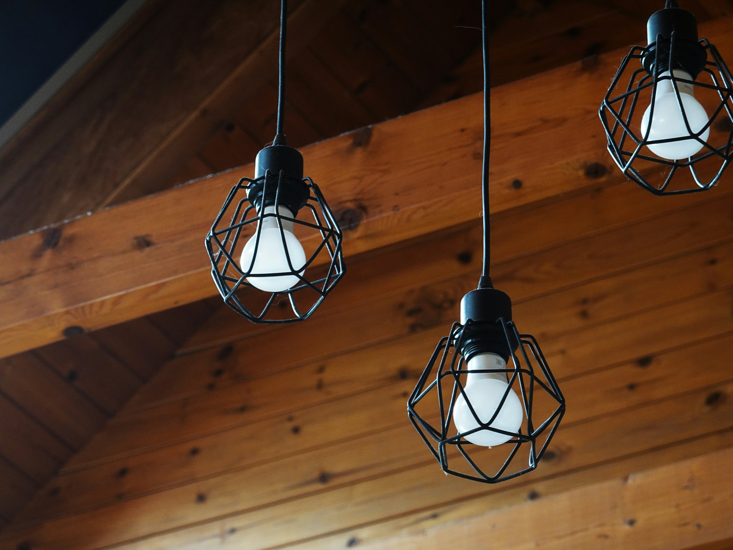 Pendant light fixtures with black wire cages — a lighting installation style Hoagie's Electric wires for residential clients.