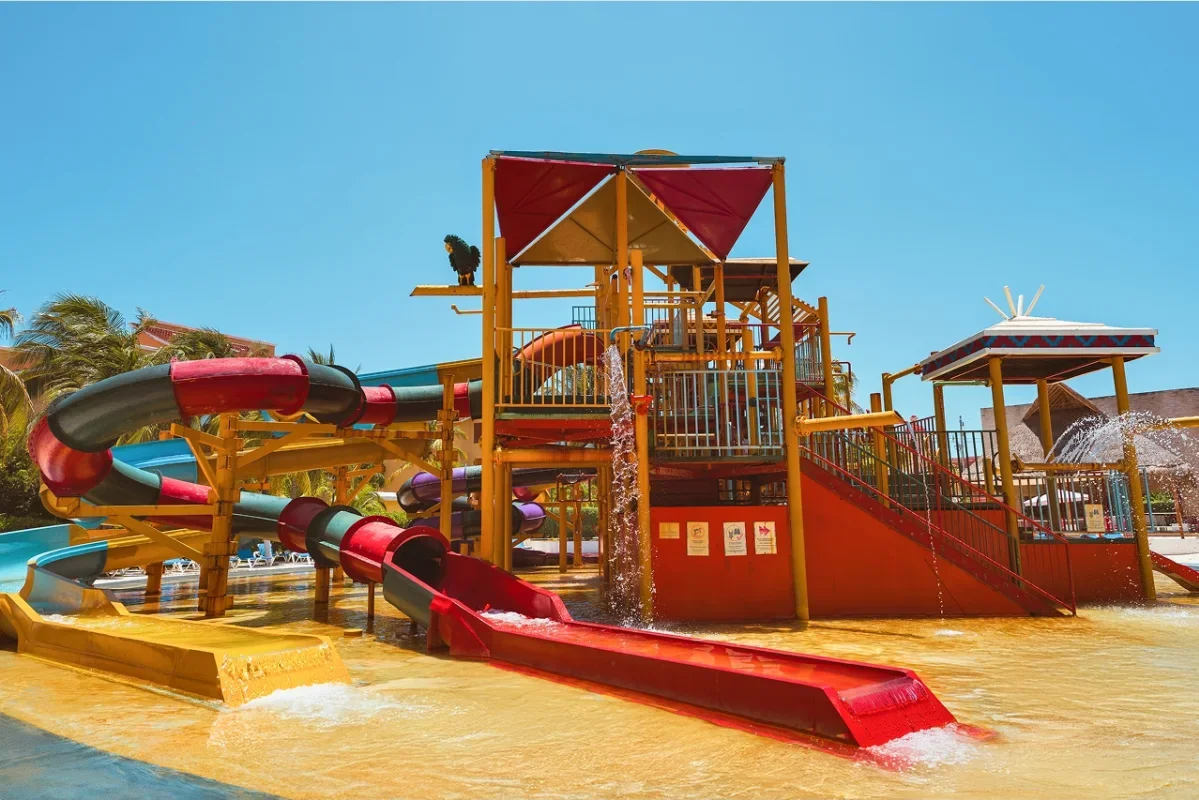 Colorful water park with multiple water slides and splash areas, under clear blue sky.