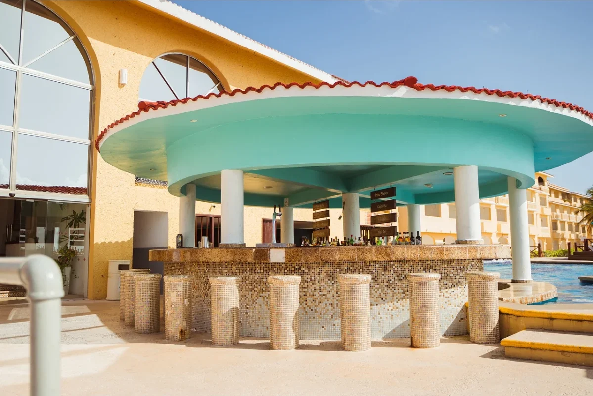 Poolside tiki bar with turquoise roof and mosaic tile facade at a resort.