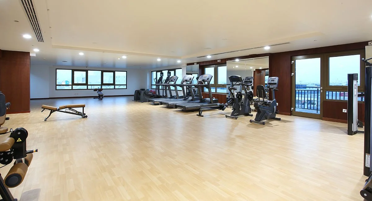 Empty indoor gym with treadmills, exercise bikes, and a weight bench.