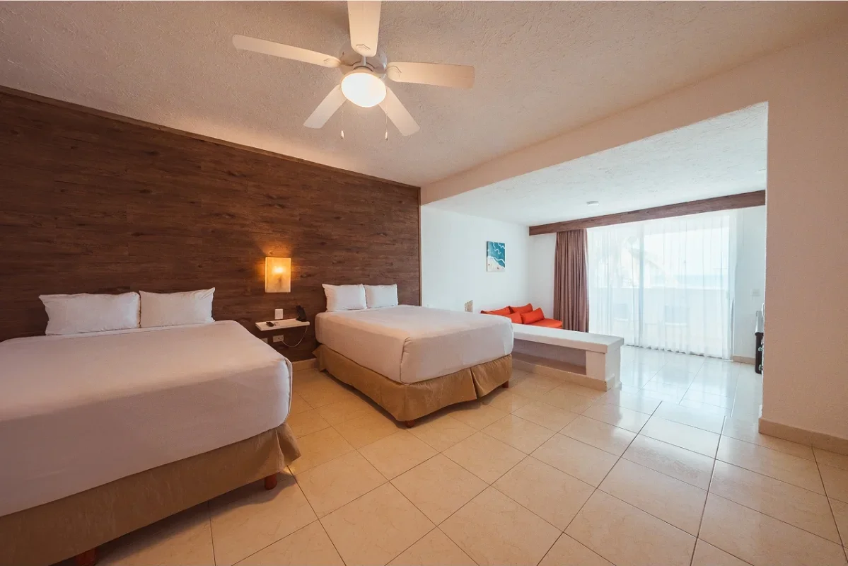 Hotel room with two beds, a ceiling fan, a sitting area with a red couch, large window with curtains.