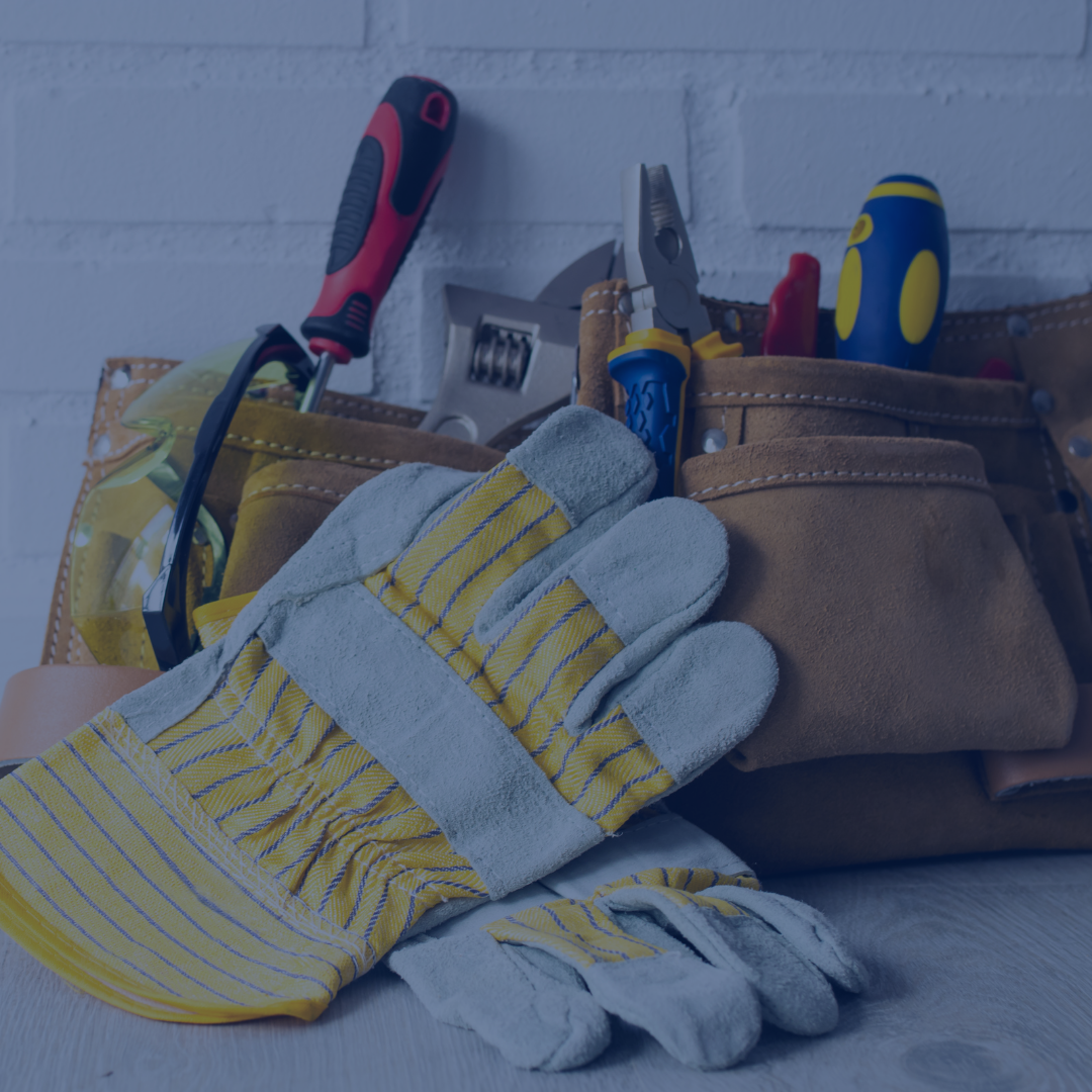 Gardening tools, gloves, and safety glasses on a work surface with a tool belt.