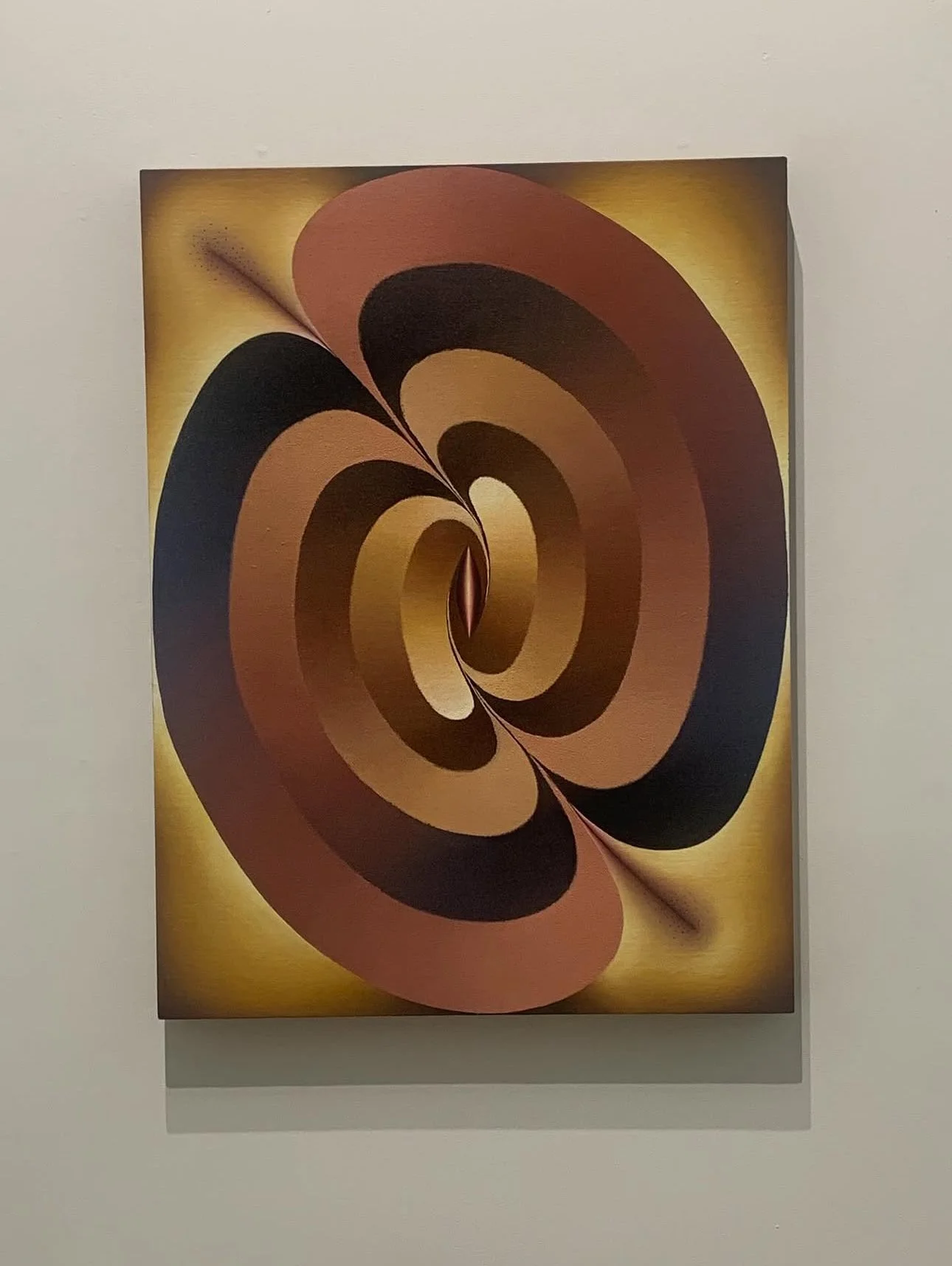 Abstract artwork featuring spiral shapes in black, brown, and tan on a golden-yellow background.