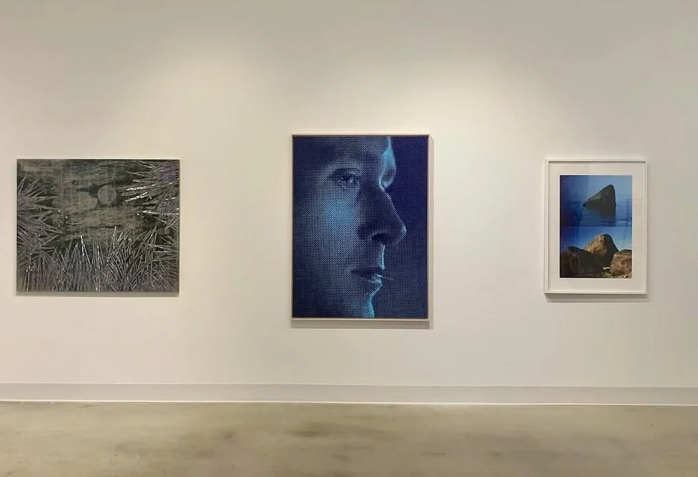 Three framed photographs displayed on a white gallery wall, with a light-colored floor below.