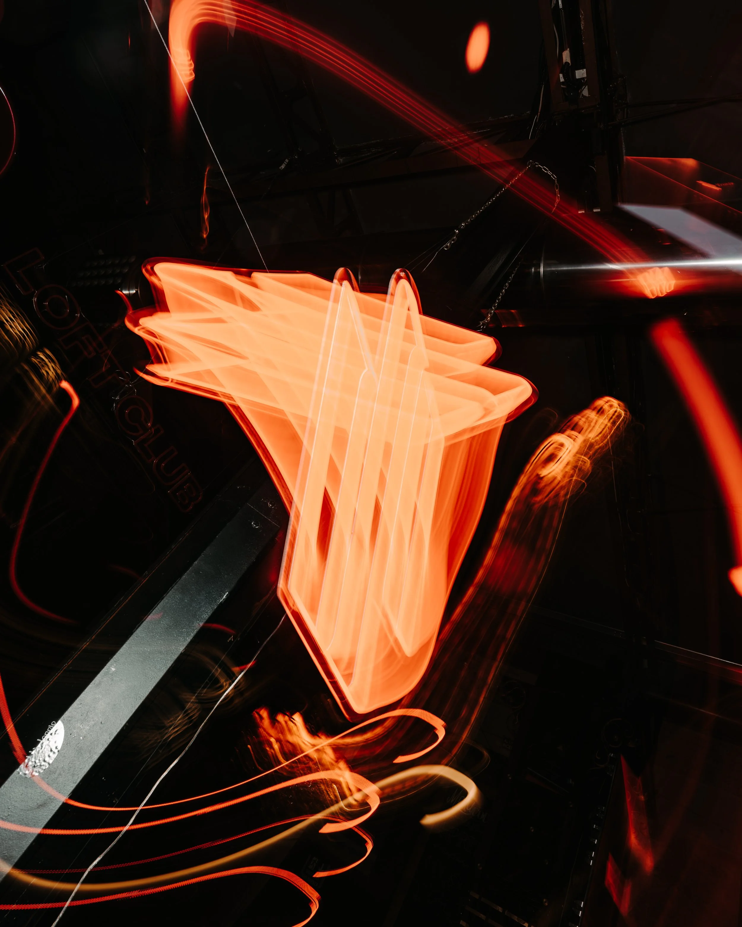 A long exposure photograph capturing streaks of orange and red light, resembling abstract light trails against a dark background.