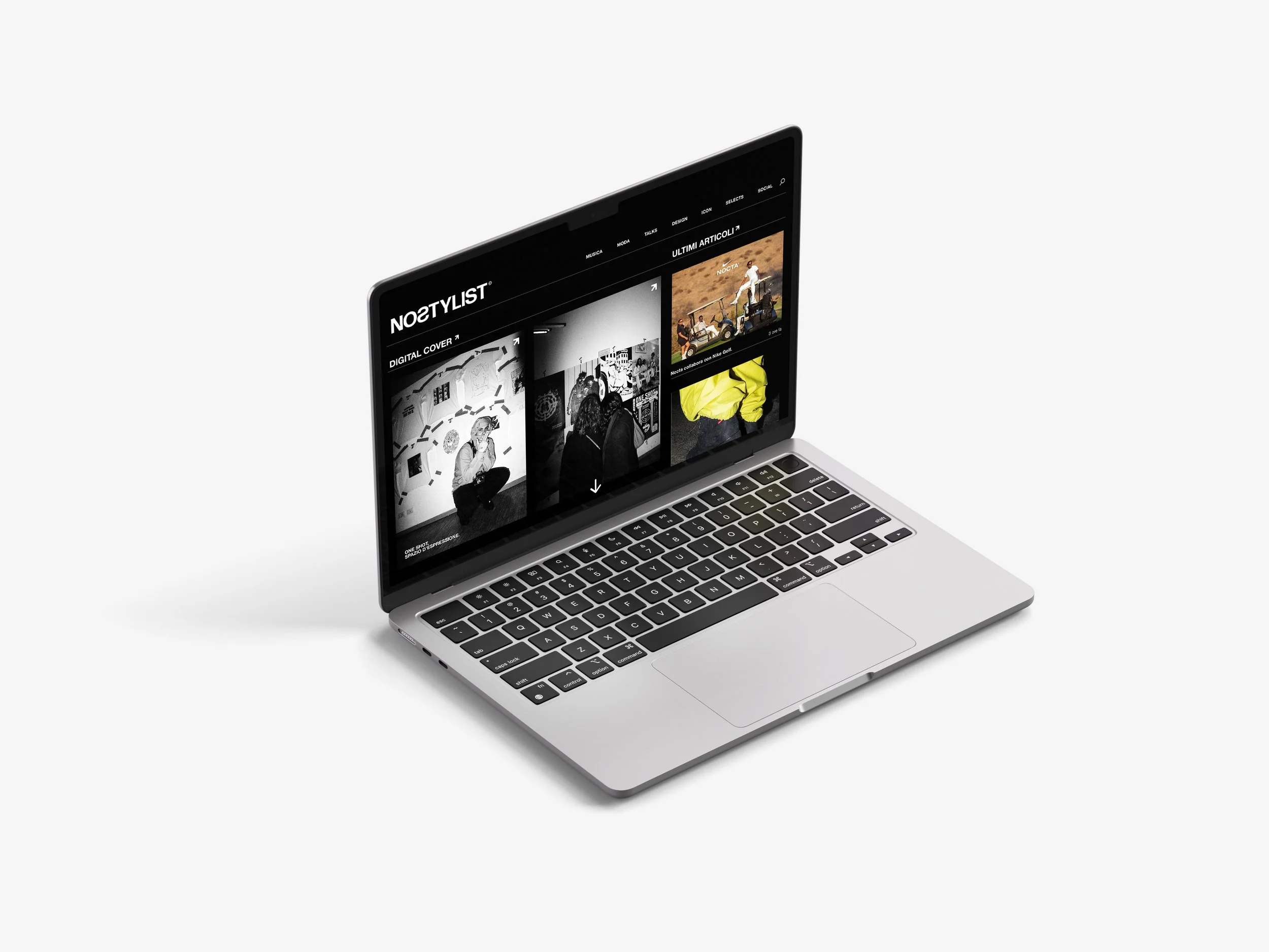 Silver laptop with a black screen displaying a website with black and white images and some colorful content on a plain white background.