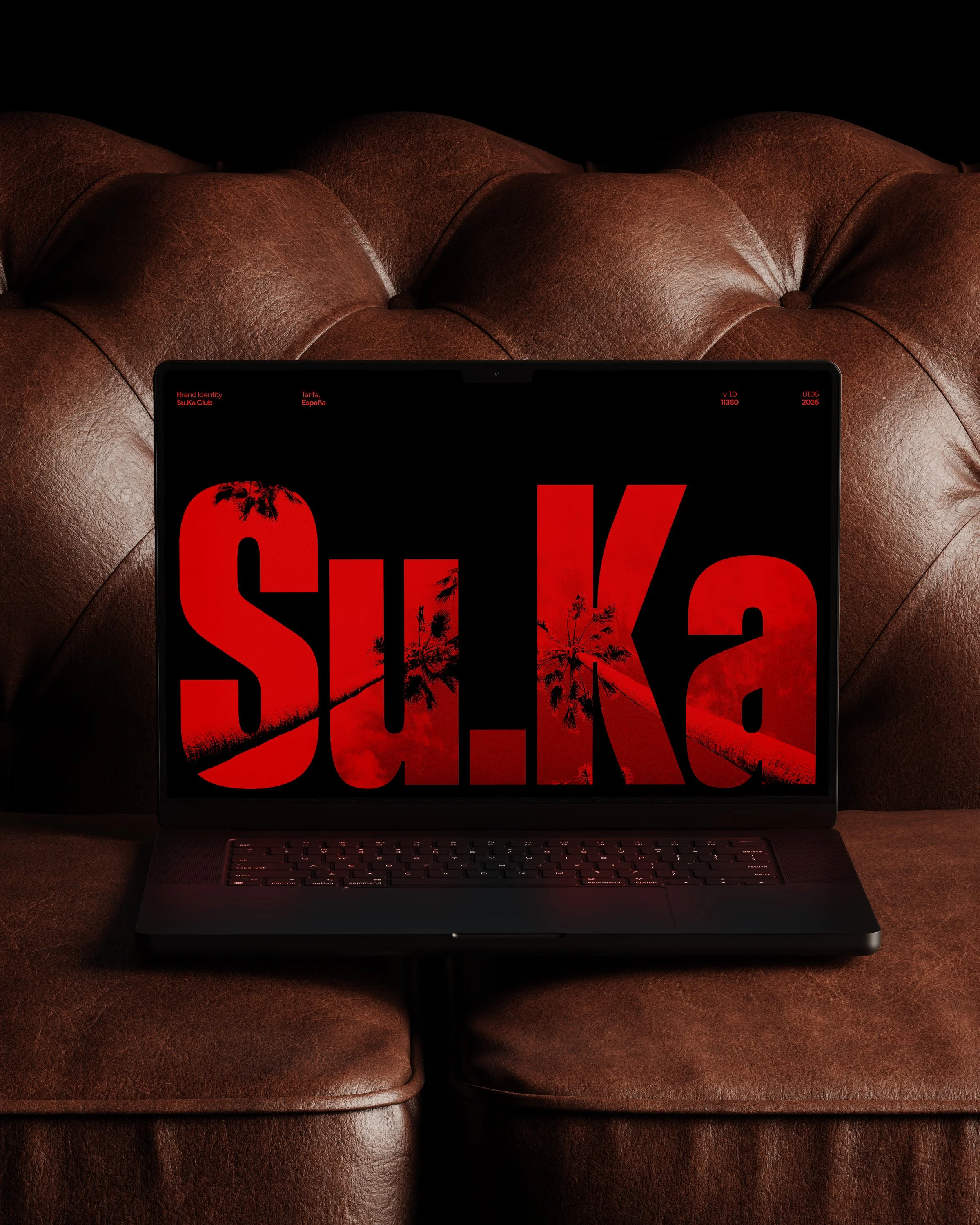 A laptop on a brown leather couch displaying a red and black graphic with the word 'Su.Ka Club' and palm trees.