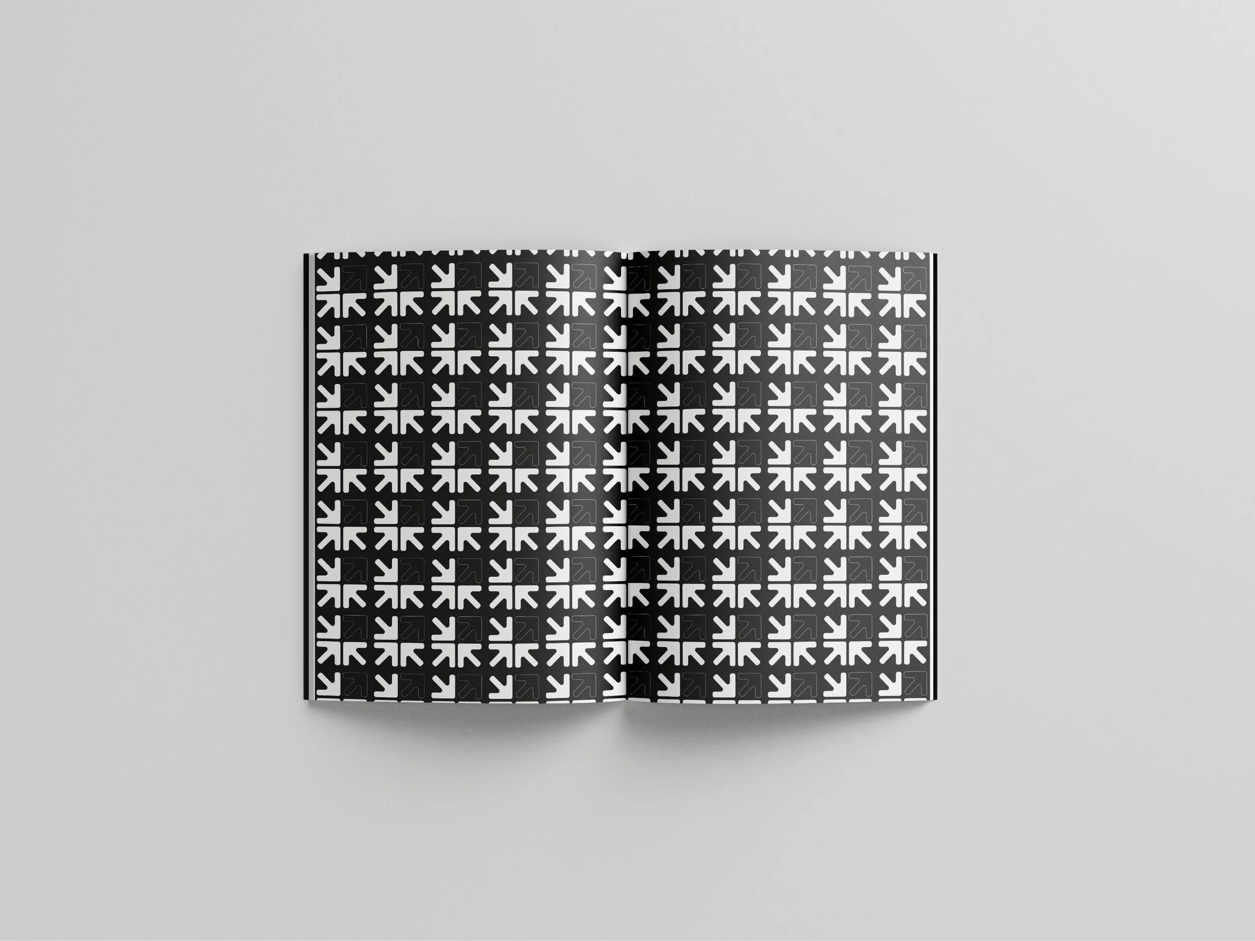 A black and white square with a pattern of arrows pointing in various directions, laying flat on a minimalist gray background.