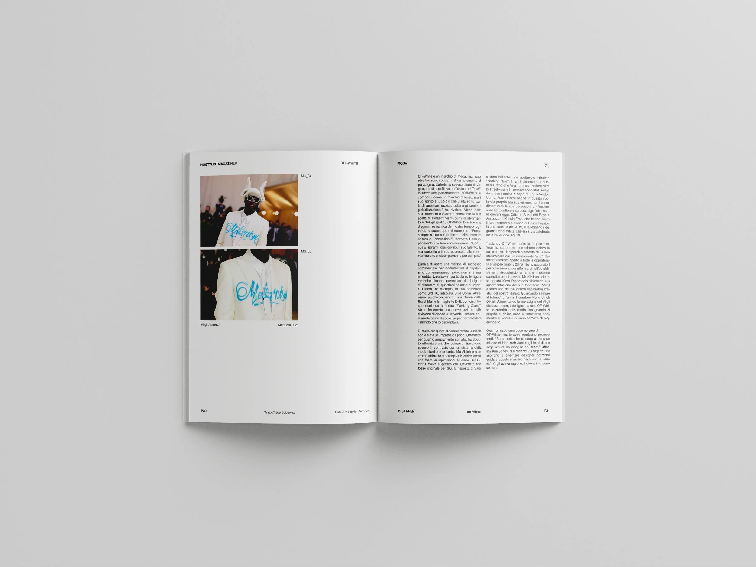 Open magazine on a plain gray background with pages featuring fashion photography and text in Italian, including images of a person in a white jacket with blue writing and animal horns.