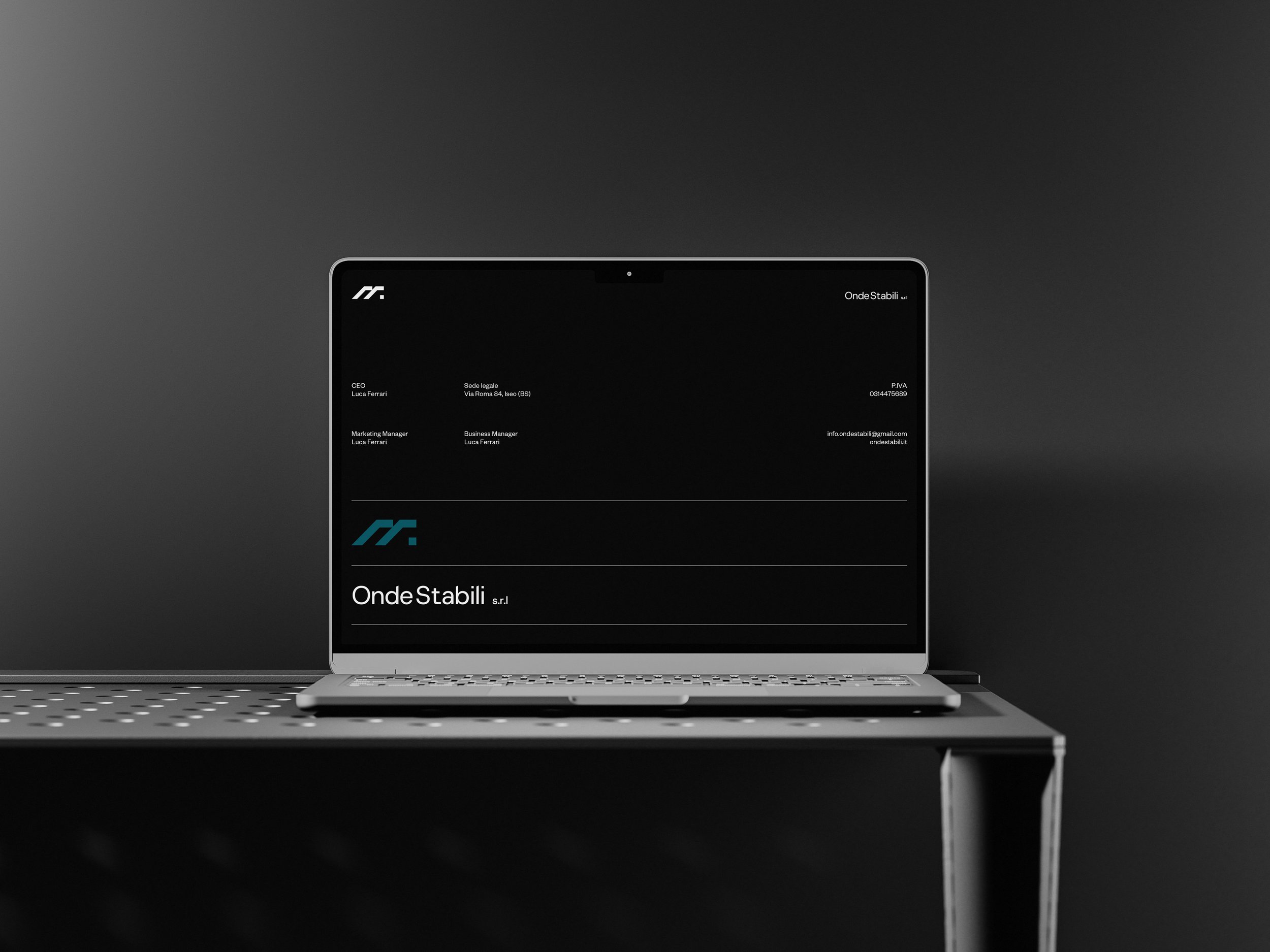 A laptop on a dark desk displaying a professional business card for OndeStabili s.r.l., with contact details and logo, against a dark background.