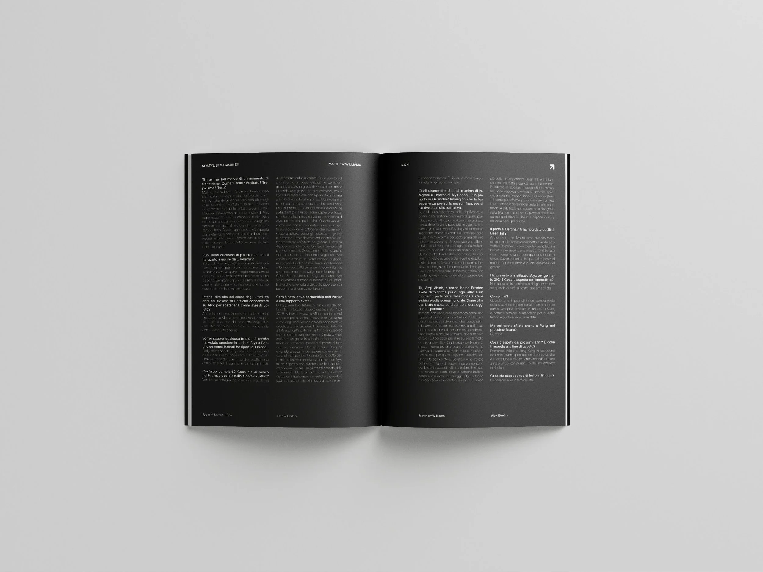Open magazine laid on a light gray surface, displaying black pages with white text in multiple columns.