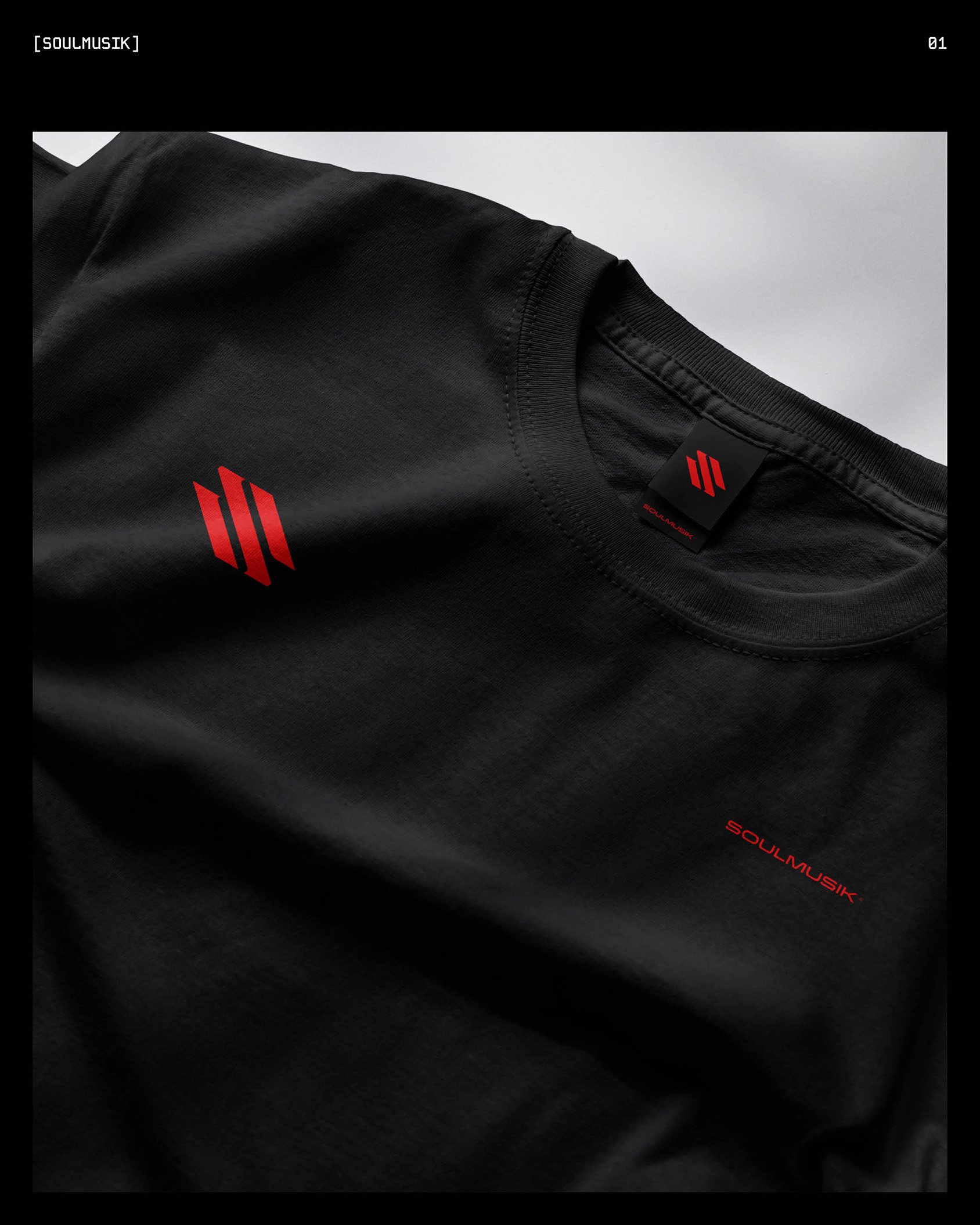 Close-up of a black t-shirt with red logo and tags, on a plain background.