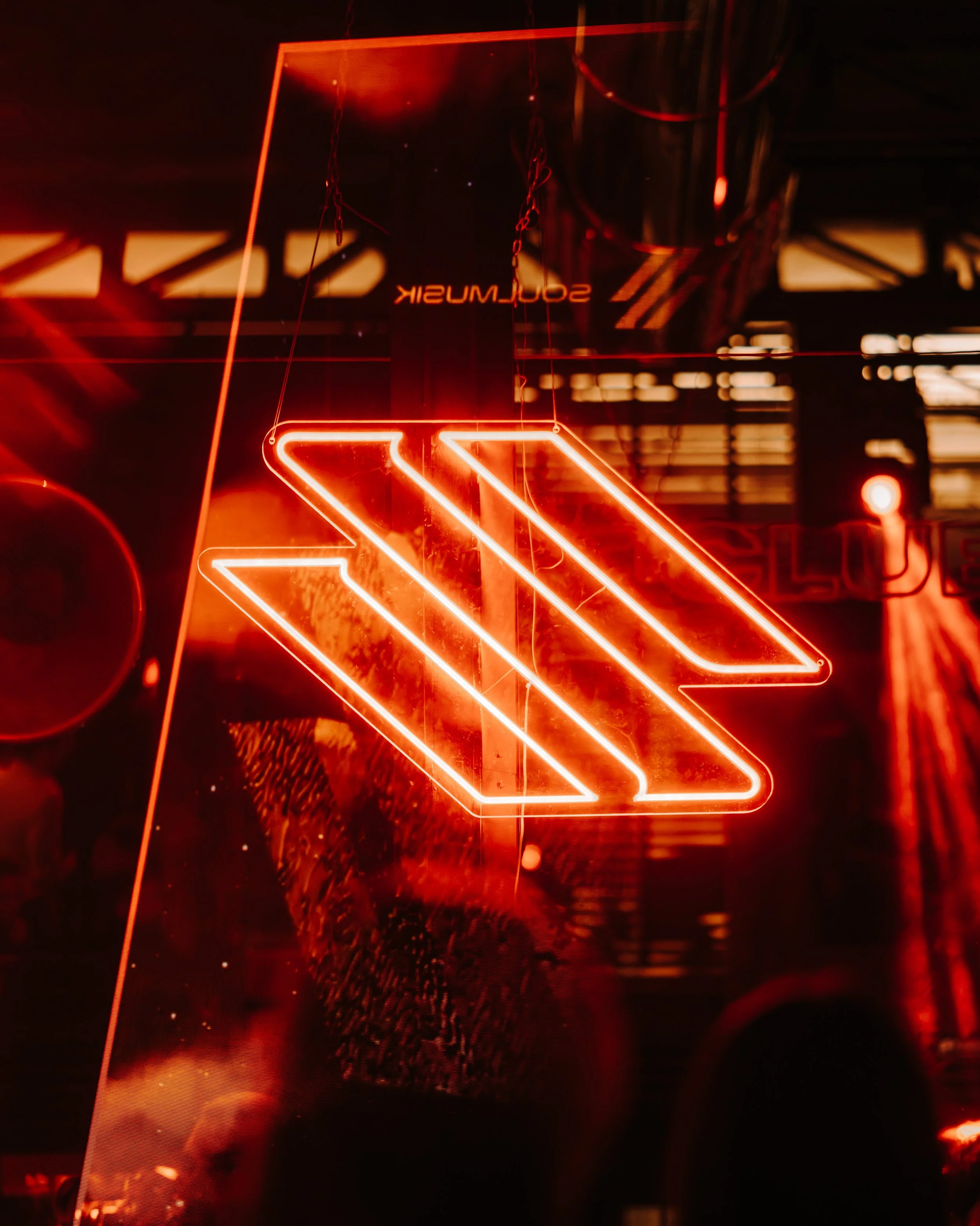 Red neon sign with the TikTok logo and the word 'SOULMUSHIK' reflected in glass.