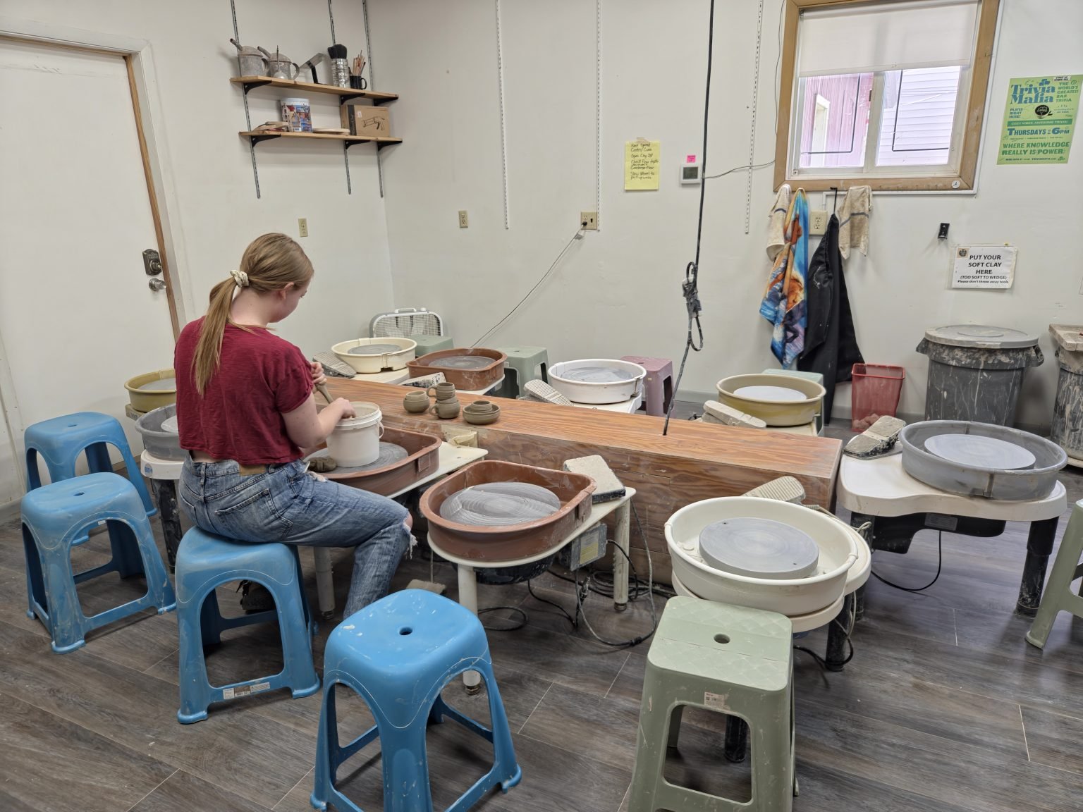 photograph of a clay studio with a person working at a wheel