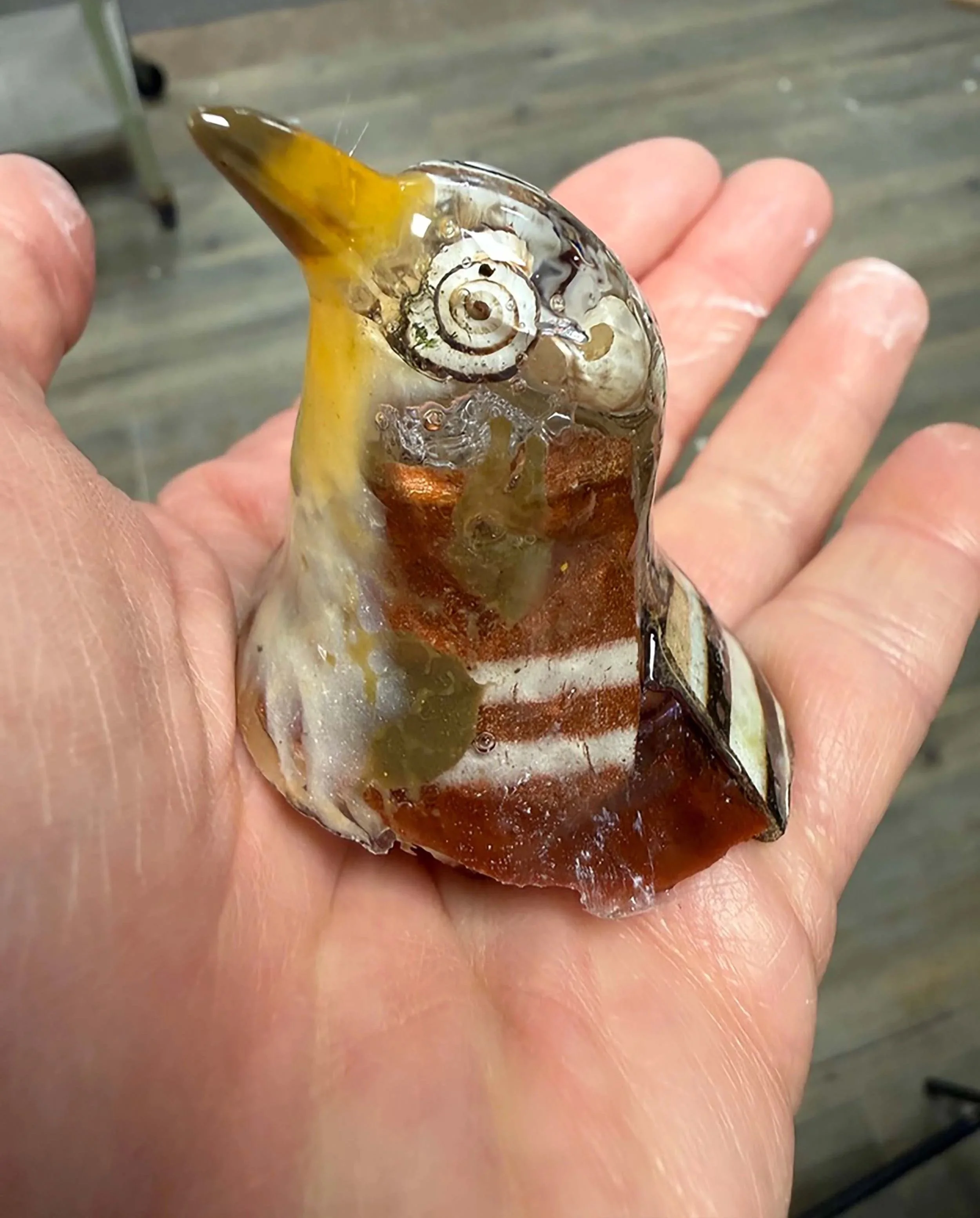 Close-up of a person holding an ammonite fossil with reddish-brown and cream-colored stripes.