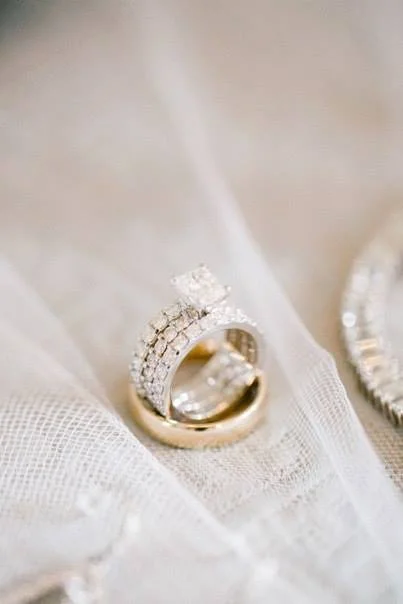 Close-up of two gold and diamond rings on white fabric.
