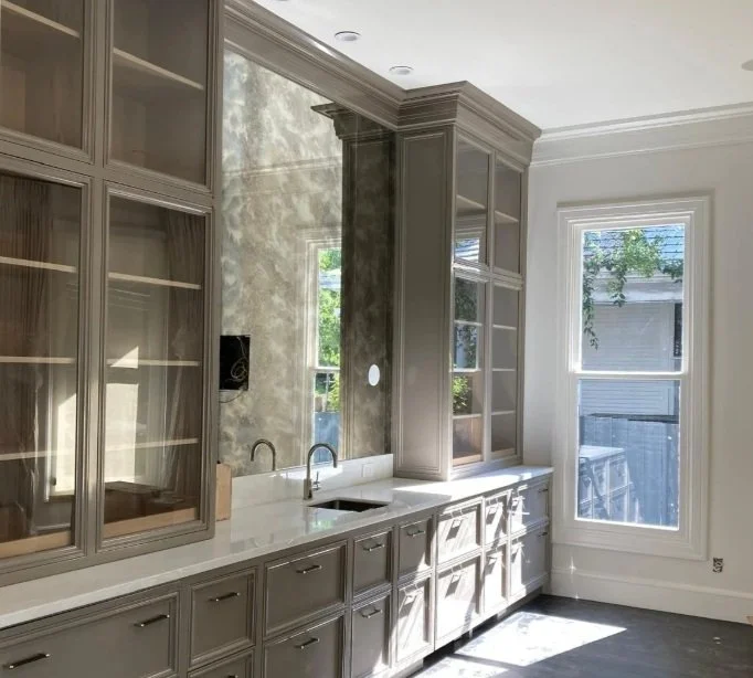 Kitchen with gray cabinets, white countertops, and a large window bringing in natural light.