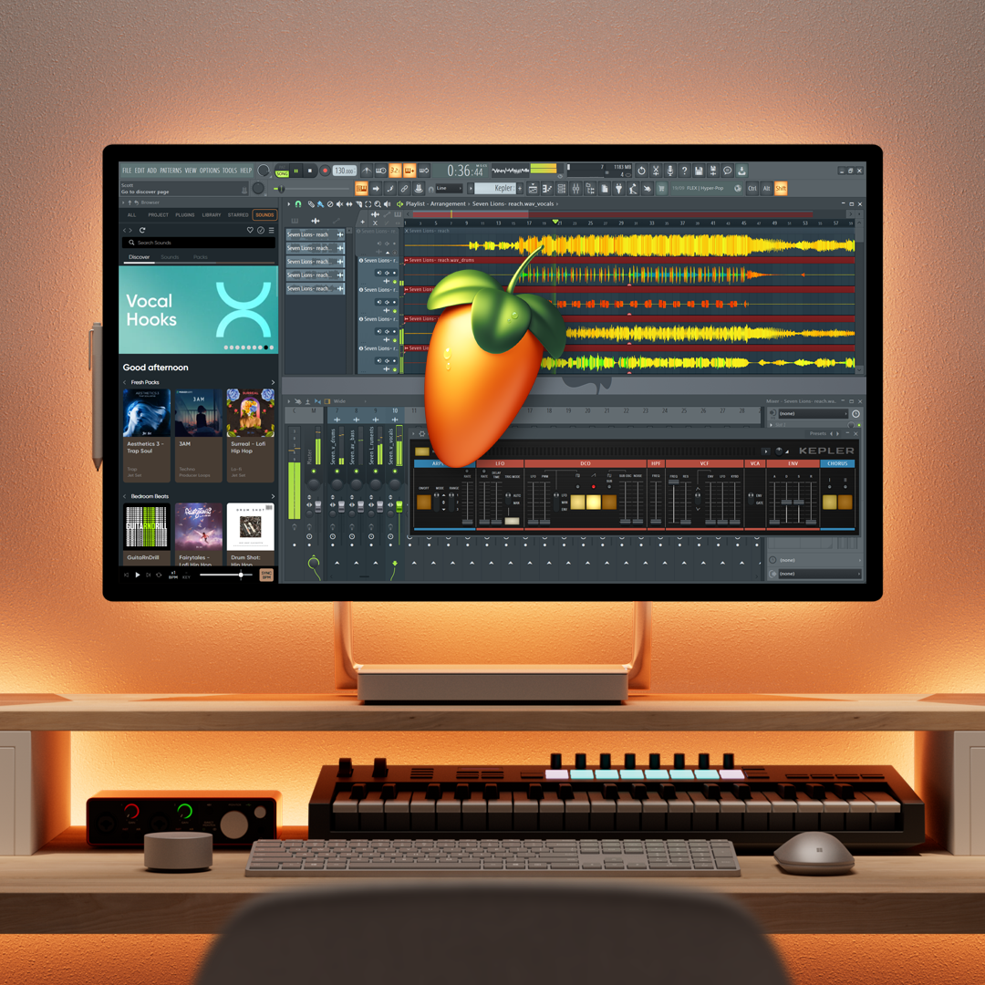 A music production workstation with a computer monitor displaying digital audio workstations, a large digital fruit logo in the center, and various music production tools on the desk.
