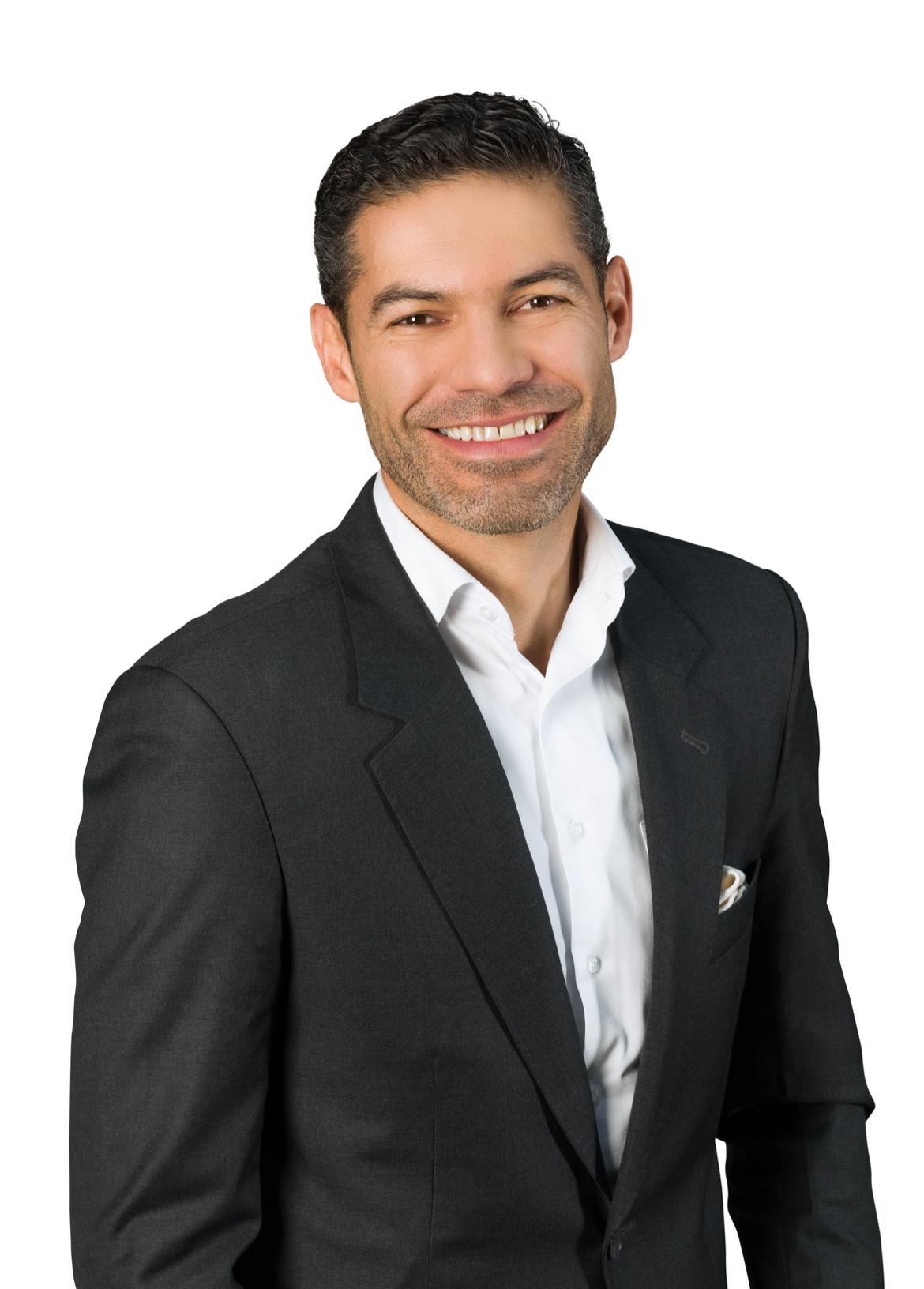 Hombre de negocios con barba, cabello oscuro y peinado hacia atrás, vistiendo saco negro y camisa blanca, sonriendo con fondo blanco.