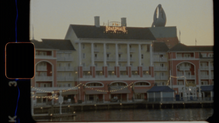 A grainy film GIF of a large building with a sign on top that reads 'Downtown' and a giant Ferris wheel in the background.