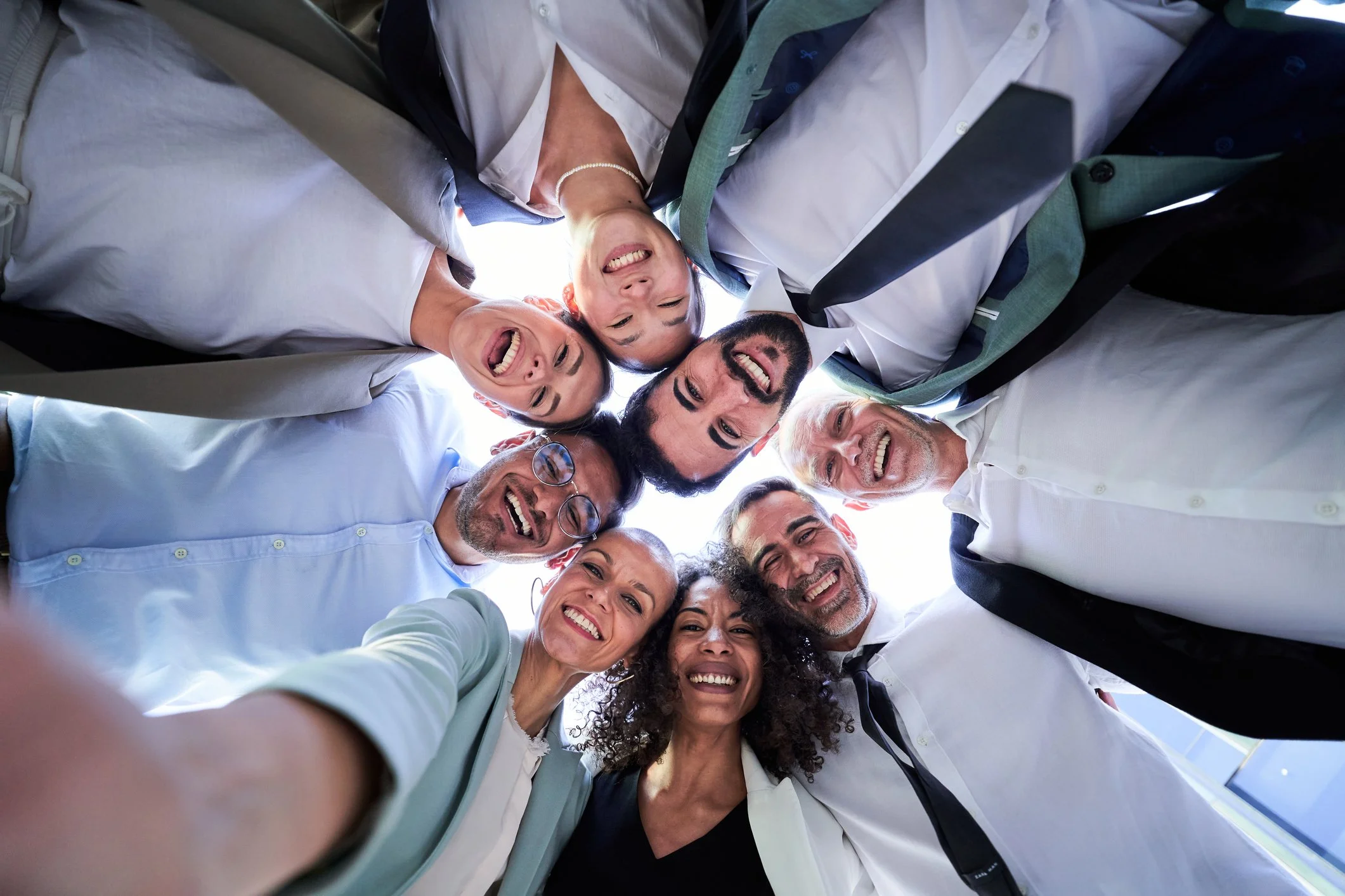 Multiethinic group of work collegues in a circle taking a selfie looking down.nt