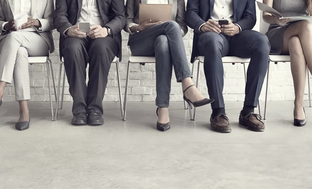 Legs of people sitting against a wall