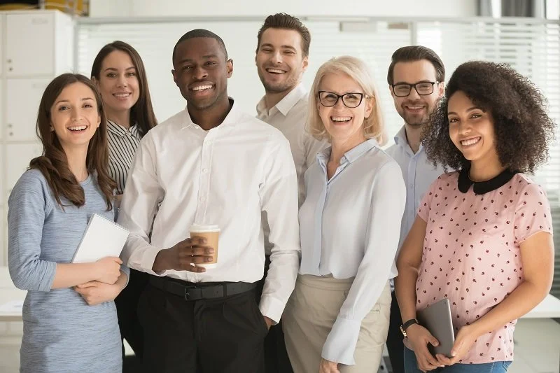 Diverse group of coworkers in casual attire smiling at the camera.