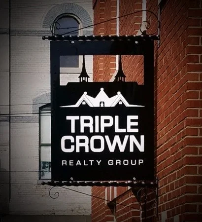 Sign for Triple Crown Realty Group mounted on a brick building wall.