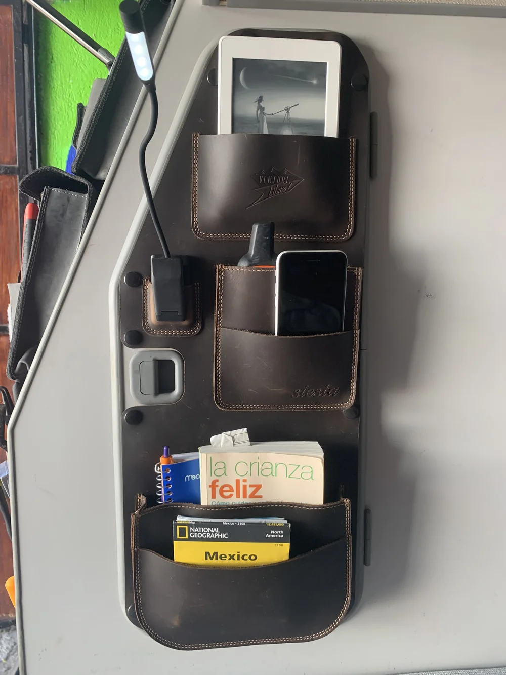 Westy Siesta leather bedside organizer mounted beside a Vanagon window with books in its lower pocket