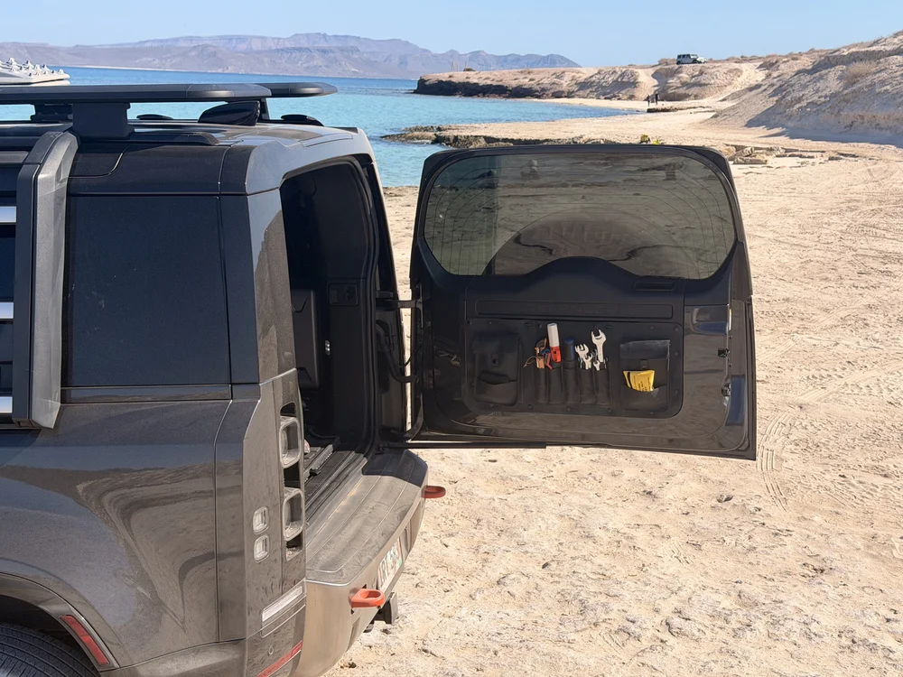 Defender Bravo leather tool organizer mounted inside the open rear door of a Land Rover Defender L663