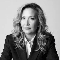Black-and-white portrait of a woman with wavy hair wearing a blazer.