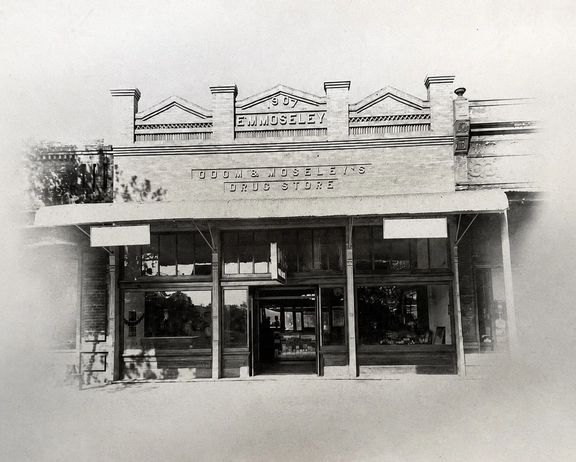 Black-and-white photo of a historic drugstore building with signs that read 'E.Moseley' and 'G.C. Moseley, Drug Store' on the facade.