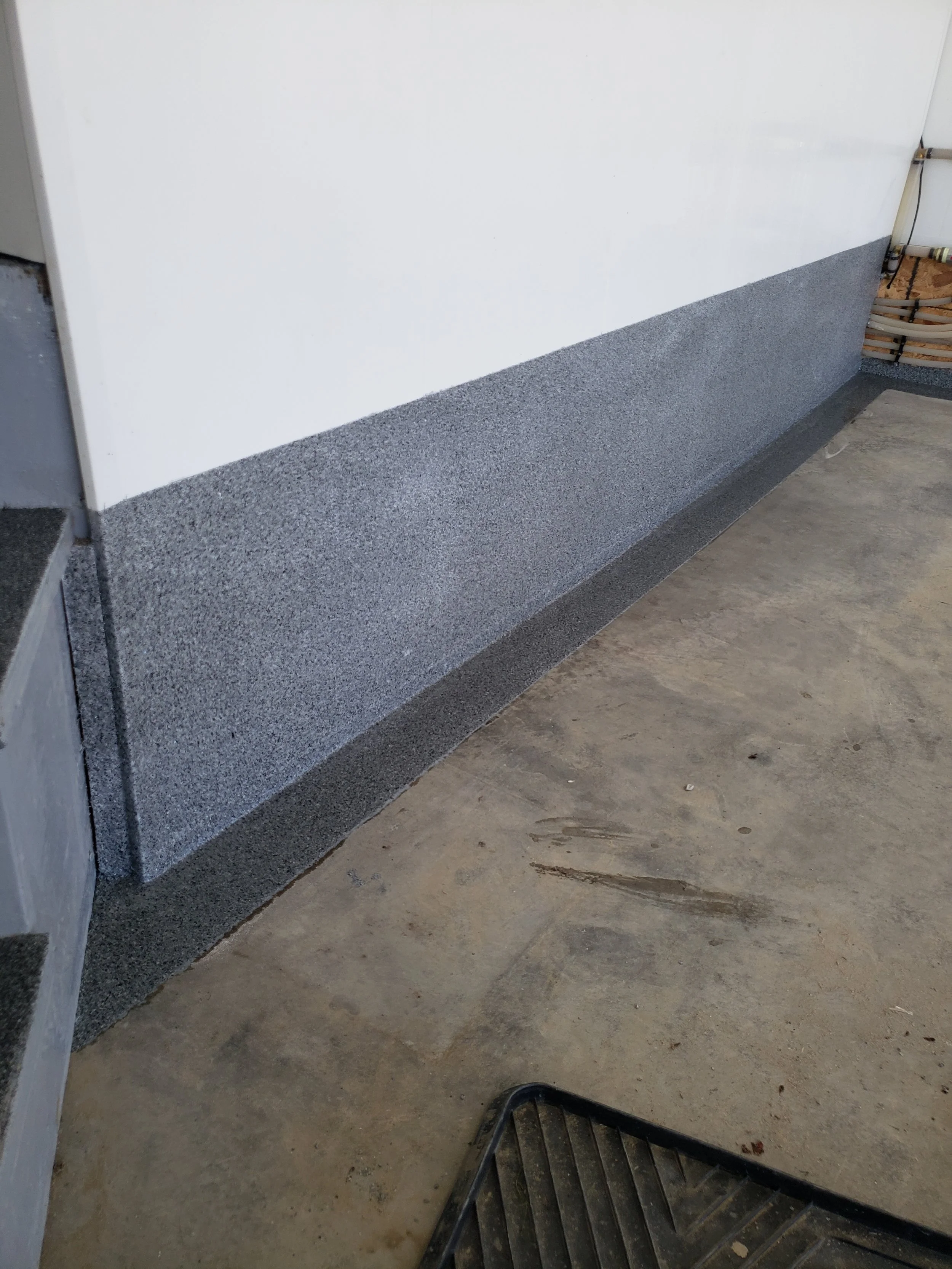 Coated garage floor curbing to seal edges. 