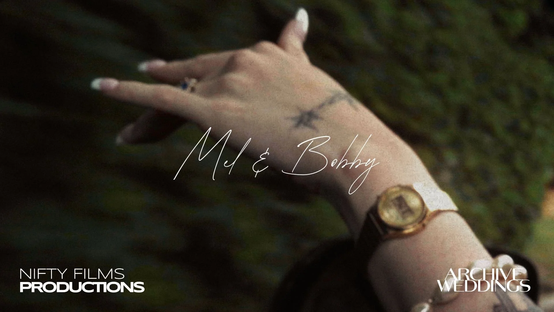 Close-up of a person's hand with a wedding ring and a star tattoo, wearing a watch, leaning on a dark surface with green foliage in the background. Overlay text reads 'Mel & Bobby' and 'Archive Weddings'.
