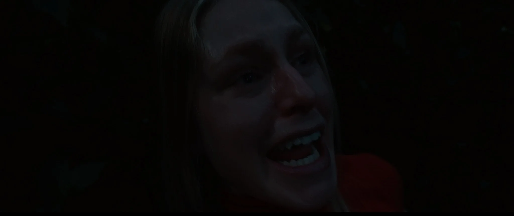 The image is very dark and difficult to see, but it appears to be a close-up of a person's face with a smile, possibly underwater or in low light conditions.