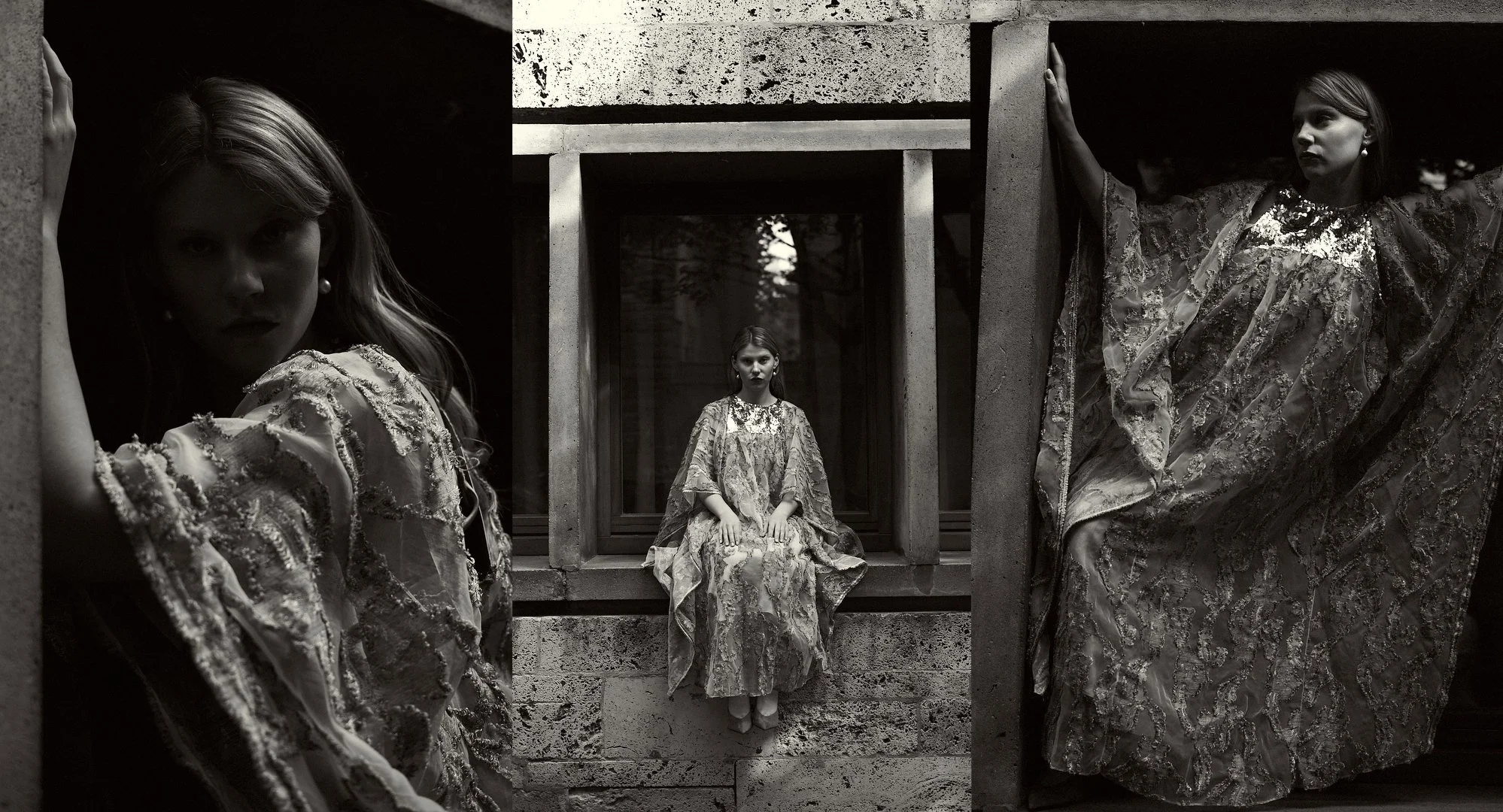 Black and white photo of three women in ornate dresses with intricate patterns, posing among concrete architectural structures, with one seated in the center and two standing on either side.