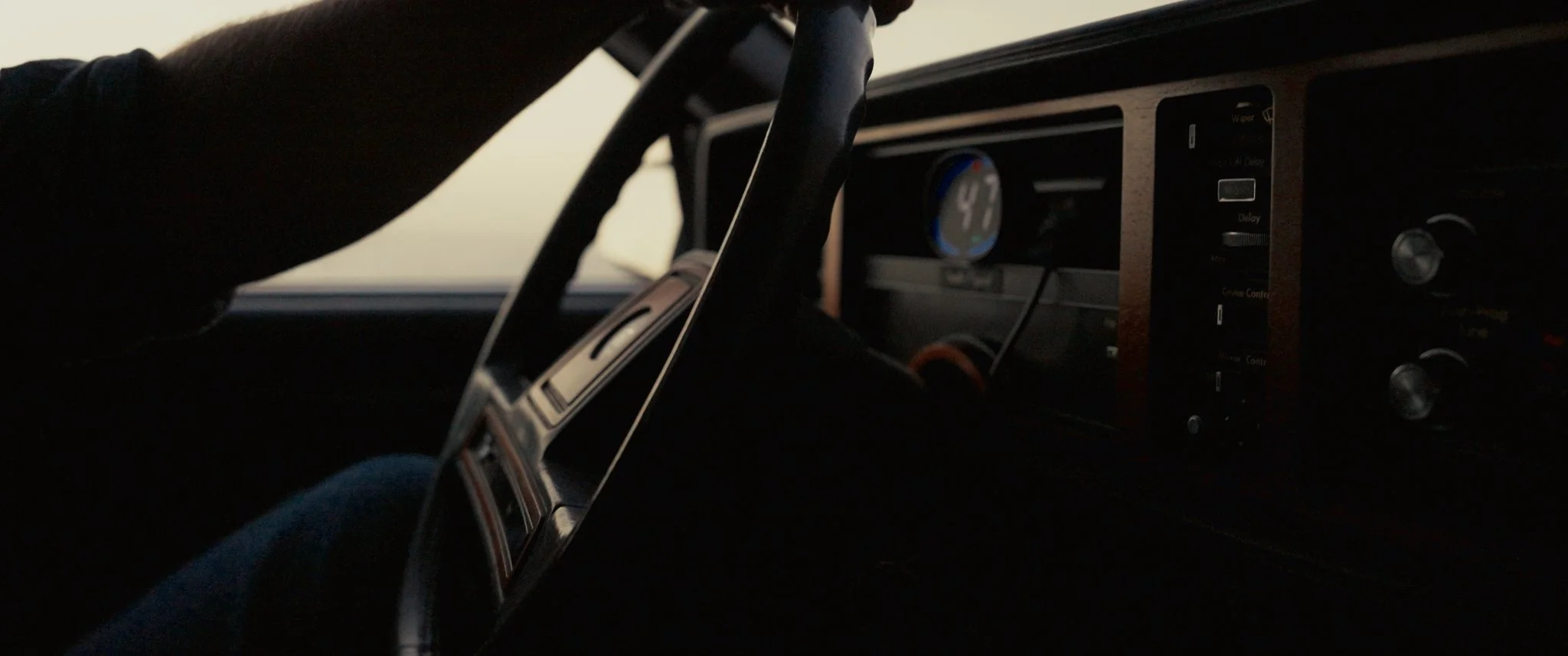 Inside a vehicle, focusing on the dashboard which displays a blue digital clock showing 4:32 and various controls.
