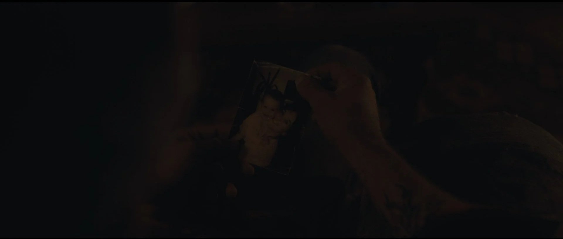 A person holding a framed photo of a young girl and smiling.